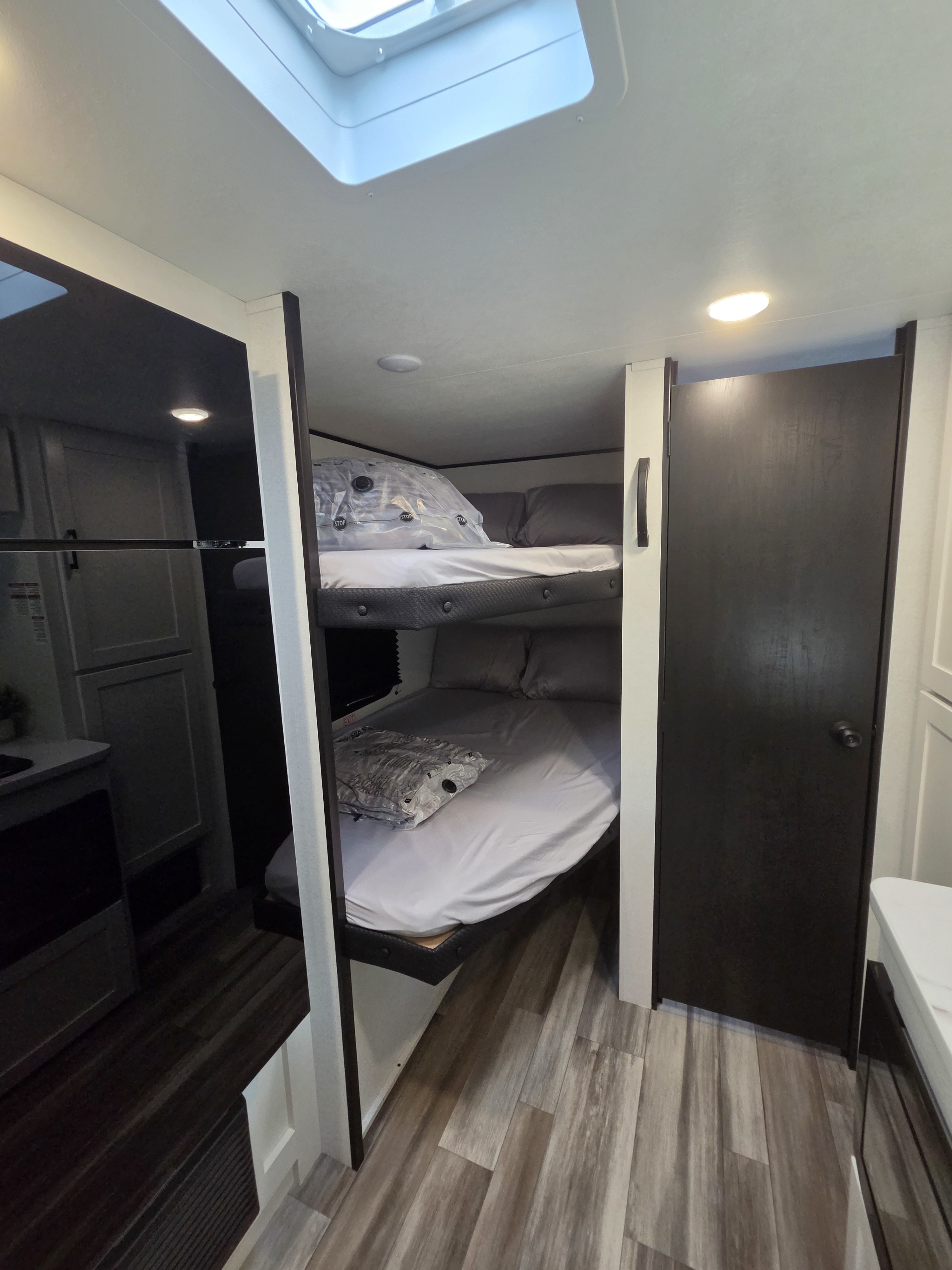 Inside an RV rental: a cozy sleeping area featuring bunk beds, a skylight, and wood-look flooring.. Jayco Jay Flight SLX Sport Edition 2026