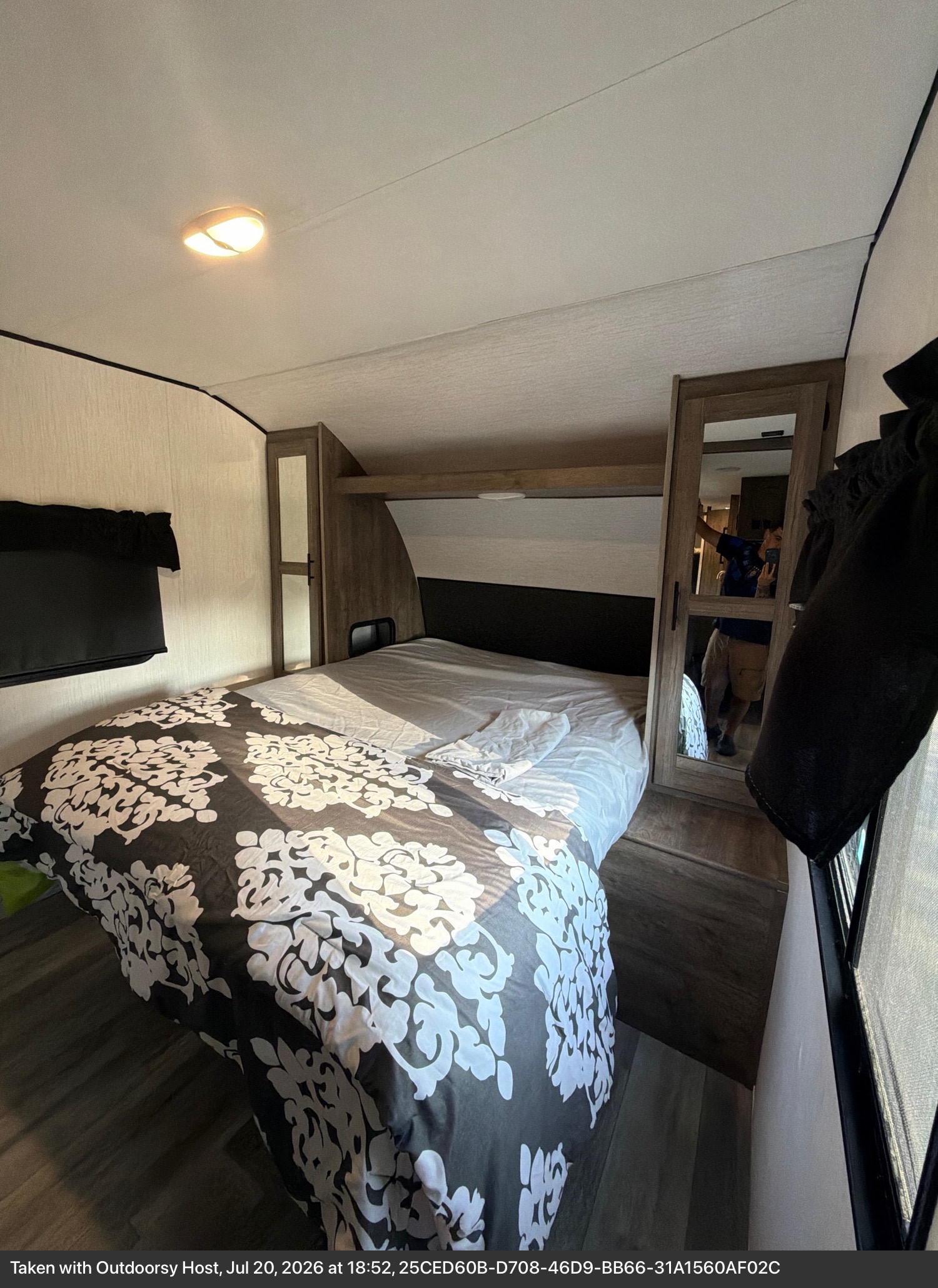 Compact RV rental bedroom with a queen bed, black & white duvet, mirrored closet & ceiling light.. Heartland RVs Pioneer 2021