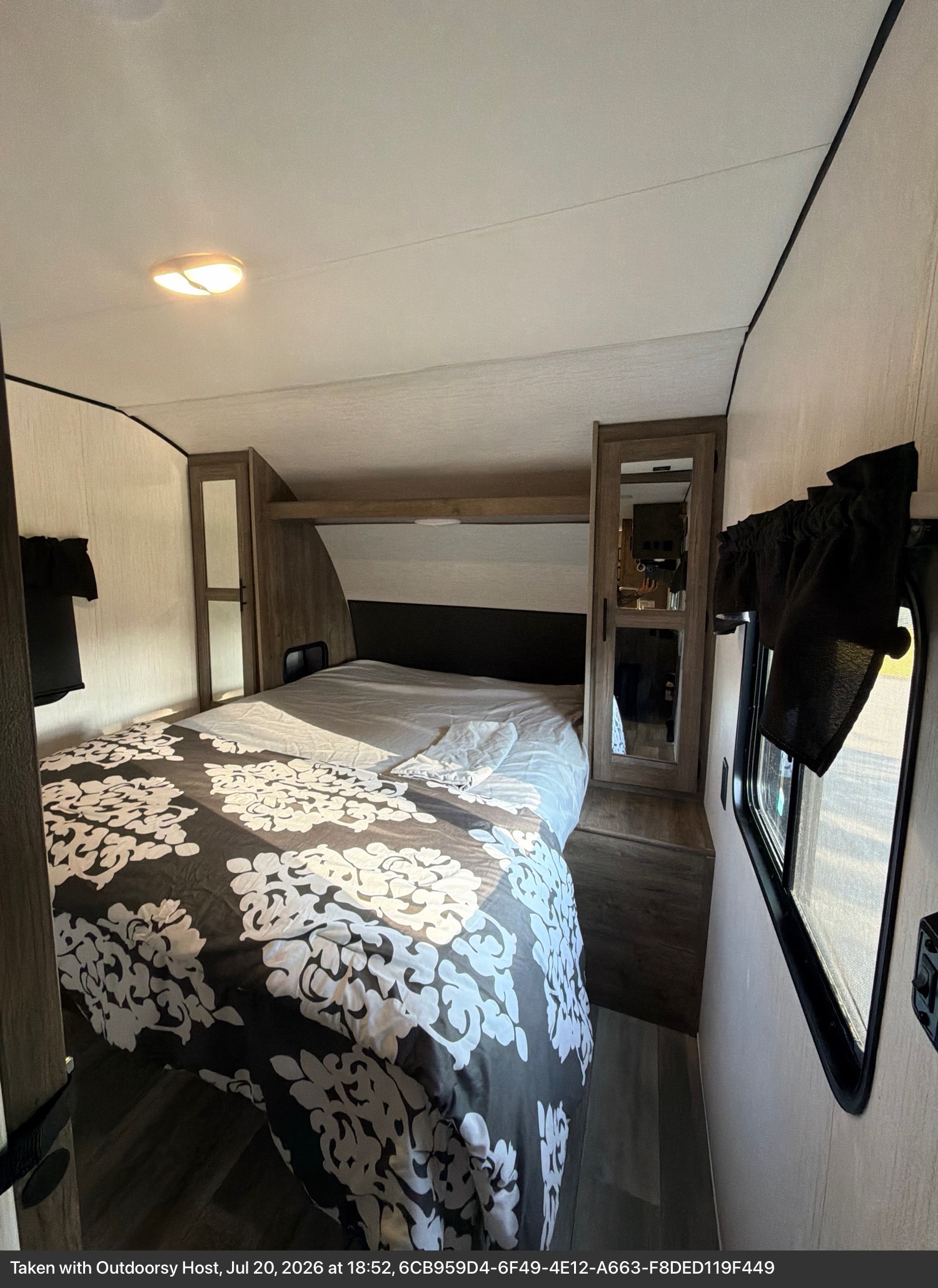 Cozy RV rental bedroom with a patterned bed, mirrored closets, and window, offering compact comfort.. Heartland RVs Pioneer 2021