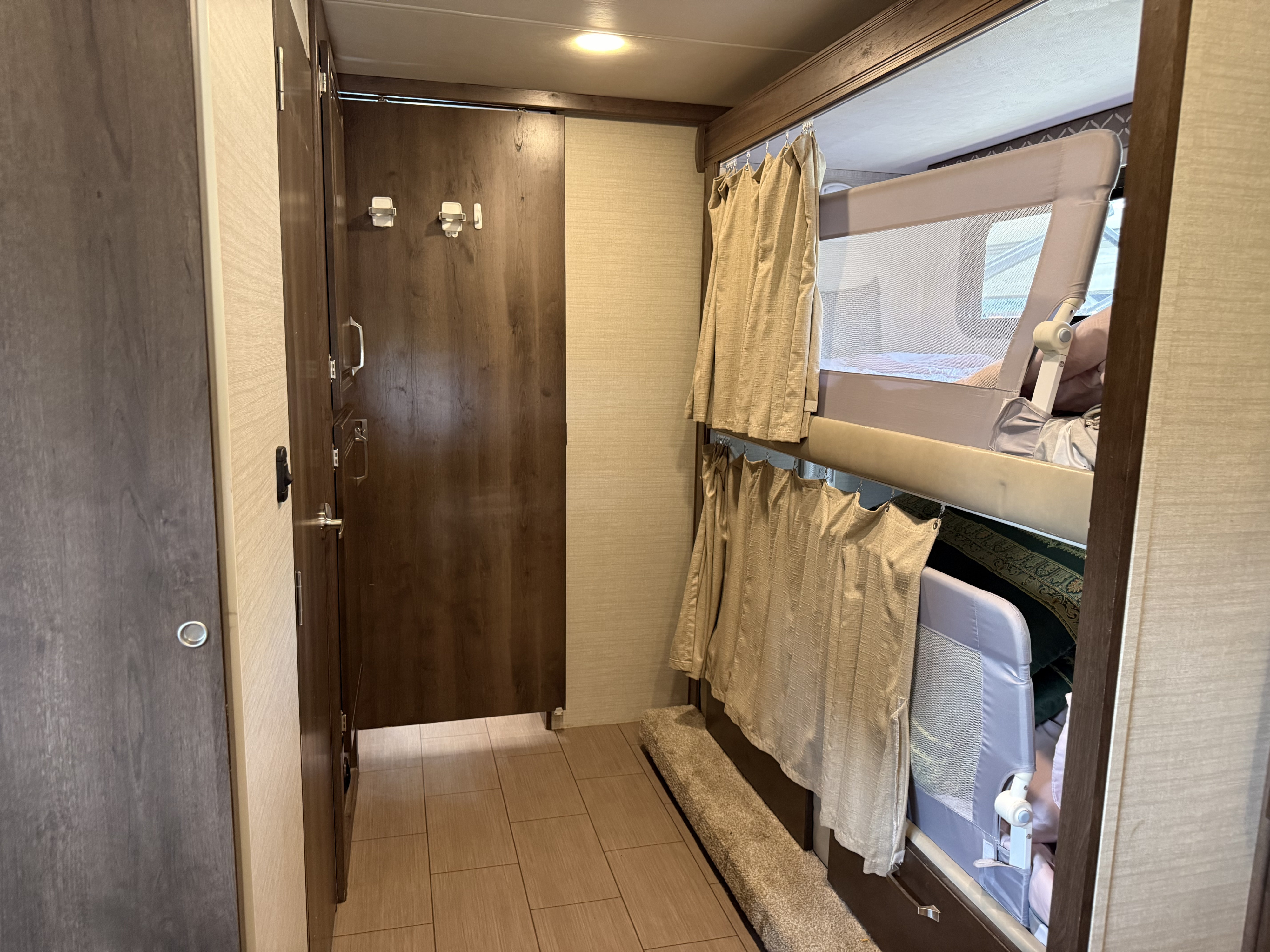 RV rental interior featuring cozy bunk beds with safety rails and privacy curtains, perfect for family camper adventures.. Jayco Greyhawk Prestige 2019