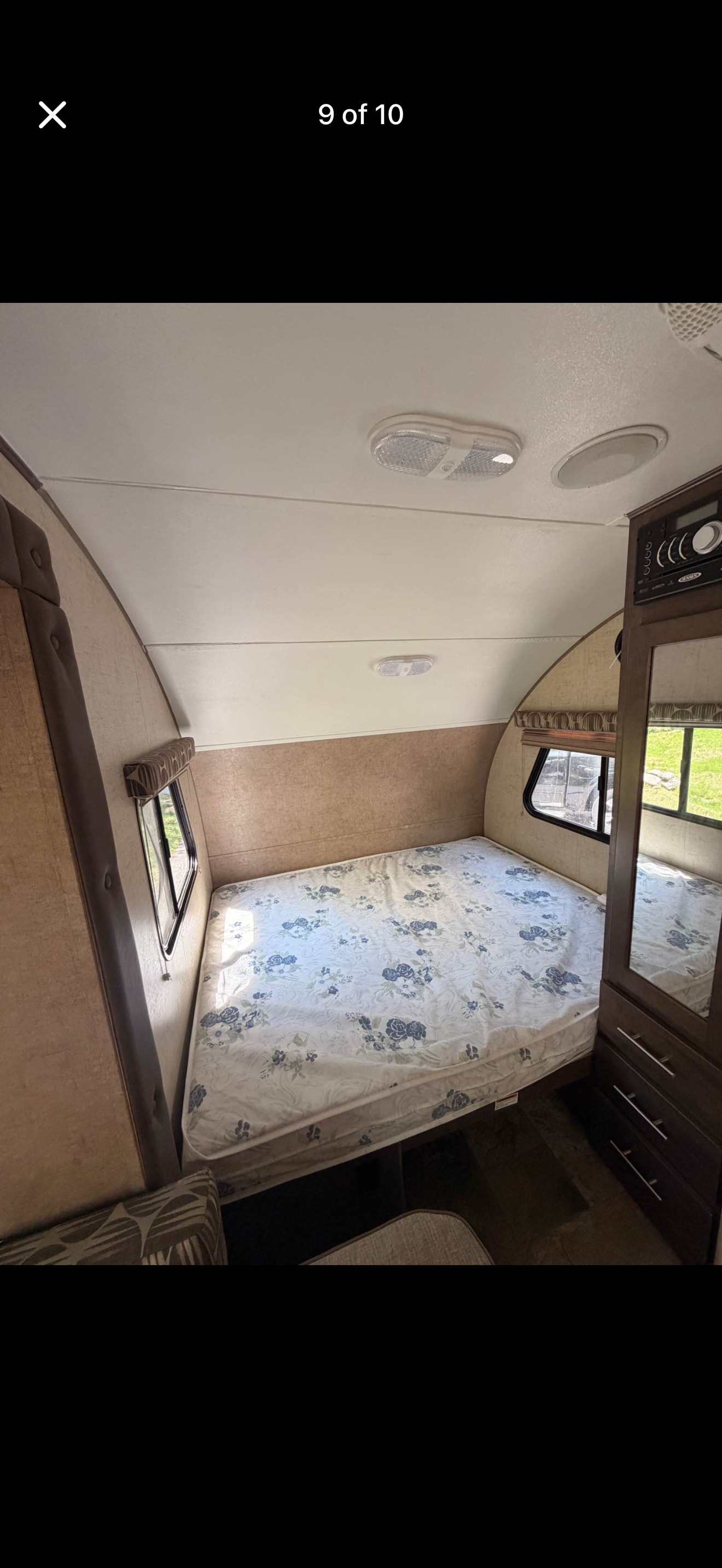 This RV rental's cozy bedroom features a floral mattress, side windows, and a built-in dresser, offering a comfortable retreat.. Forest River R-Pod 2016