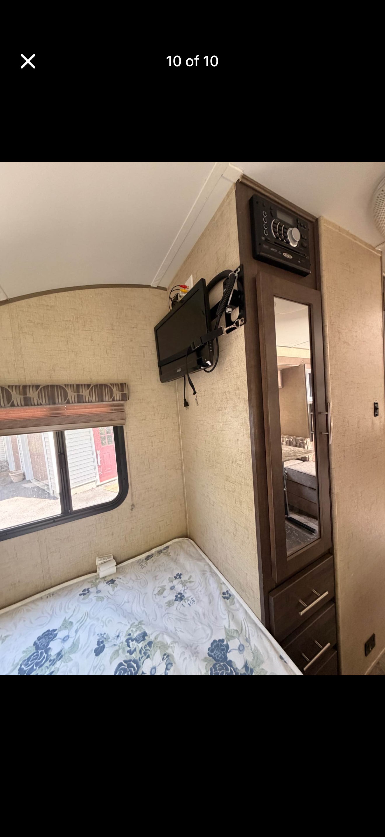 RV rental bedroom with bed, window, TV, and entertainment system above a mirrored wardrobe. Cozy travel space.. Forest River R-Pod 2016