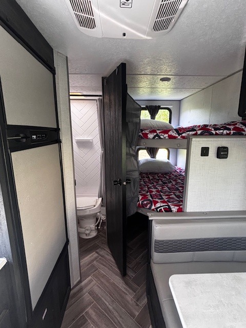 RV rental interior featuring bunk beds, dinette, refrigerator, and a compact bathroom with a toilet and shower.. Forest River Wildwood 2020