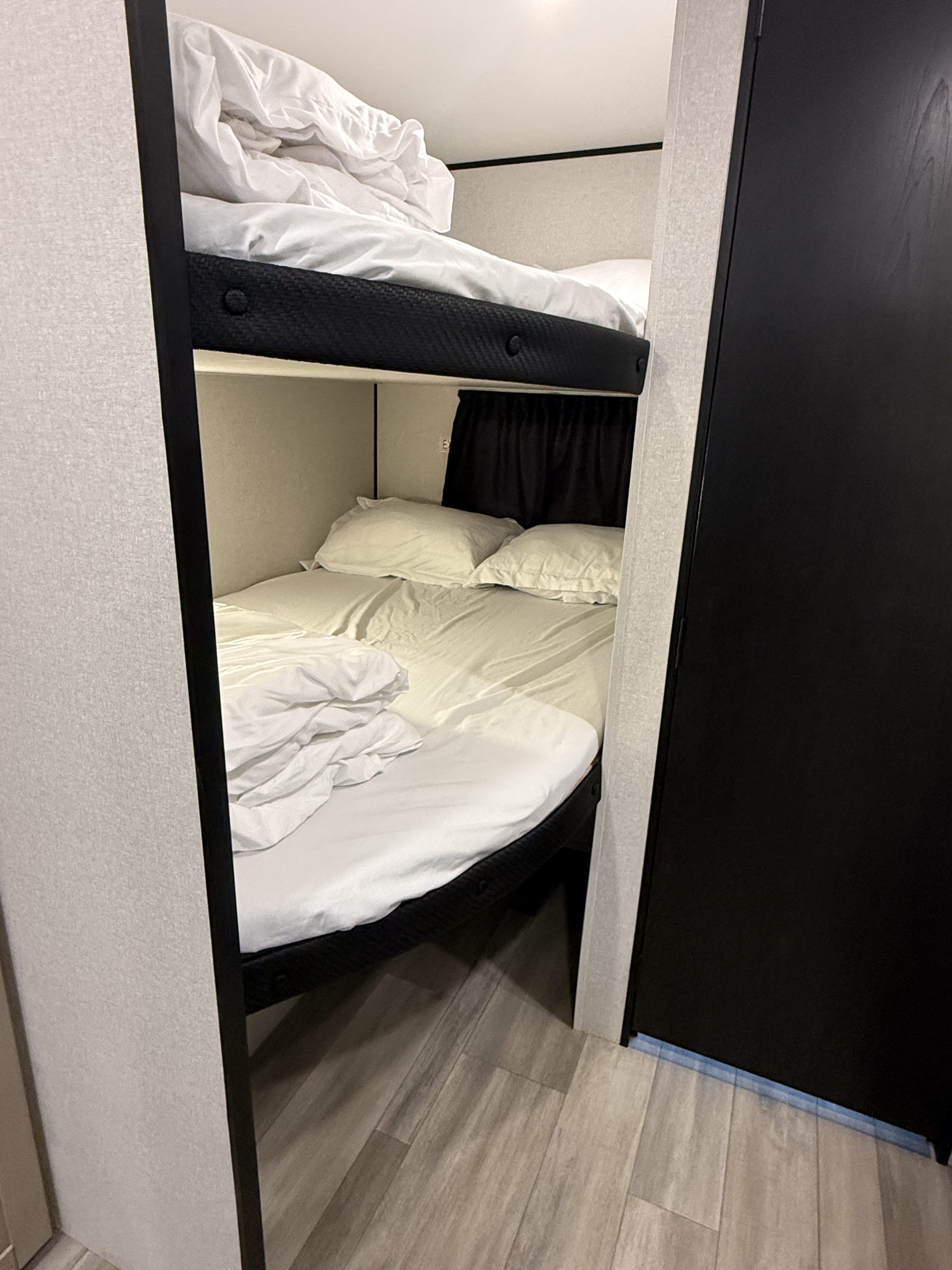 This RV rental features stacked bunk beds, made with crisp white sheets, a dark privacy curtain, and modern flooring.. Heartland Powler 2026