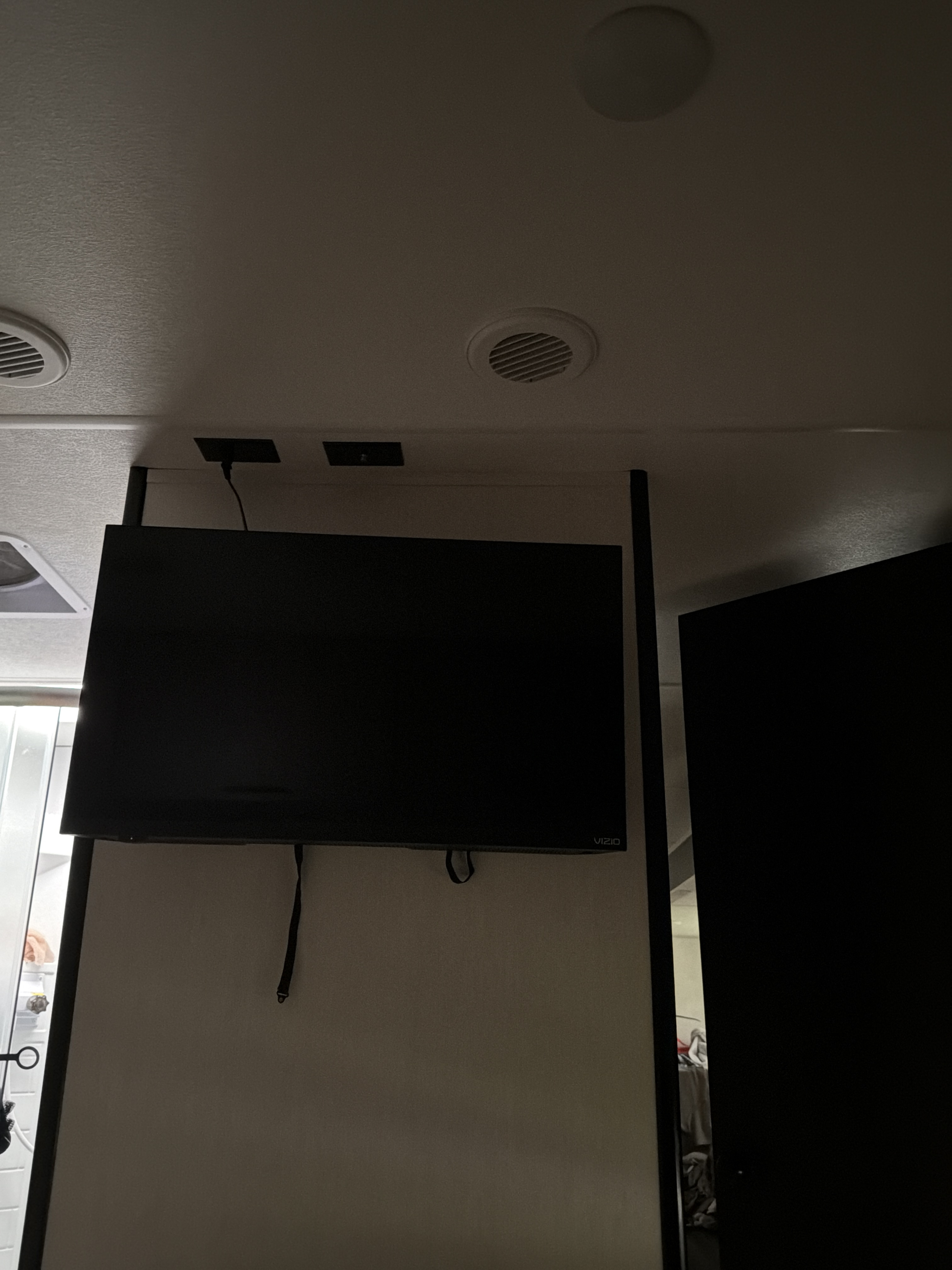 Inside an RV rental: A Vizio TV is mounted on a divider, with ceiling vents and power outlets visible overhead.. Forest River Cherokee Grey Wolf 2026