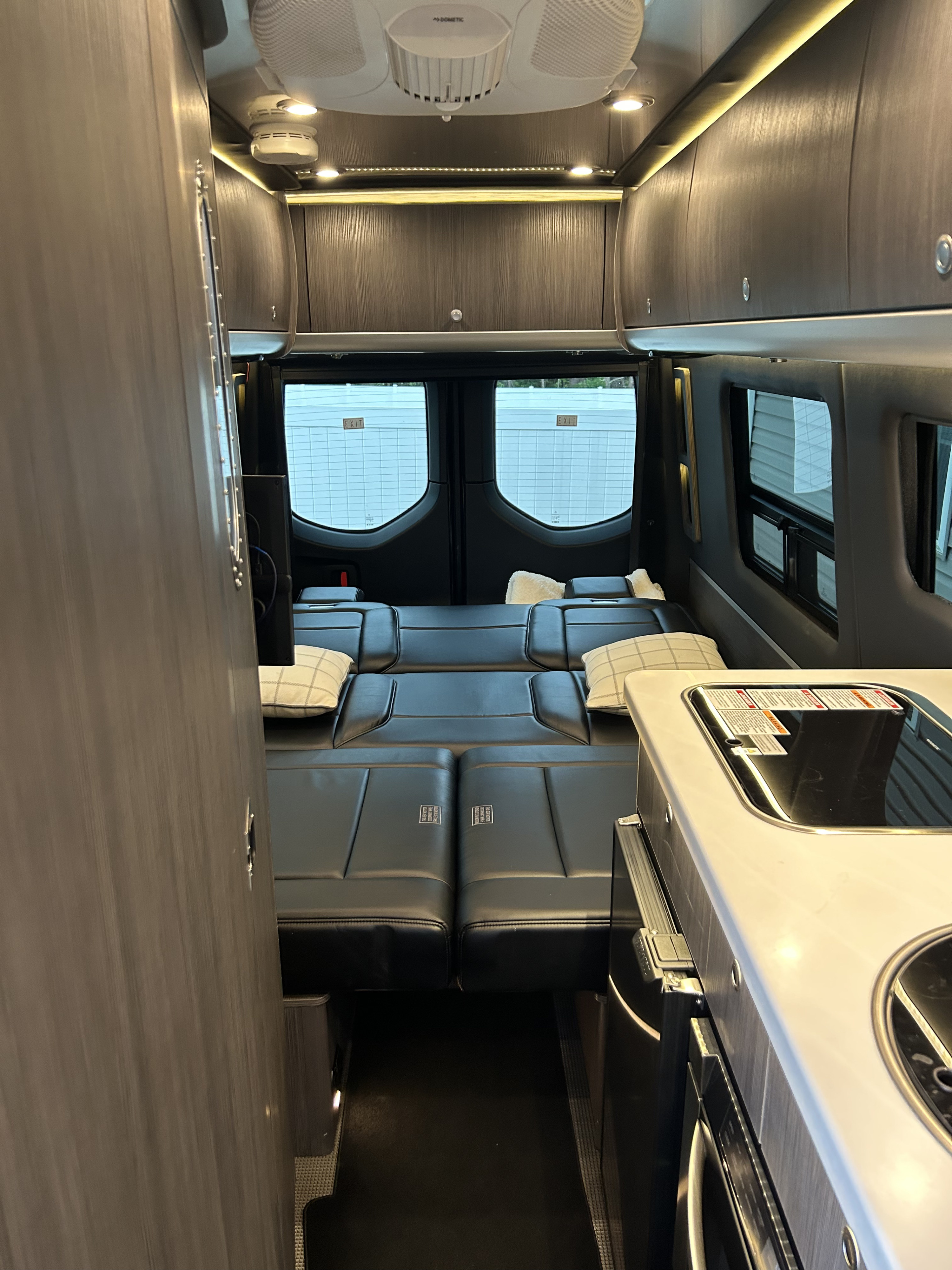 Modern RV rental interior: black convertible seating, galley kitchen, and overhead storage. Travel-ready comfort!. Airstream Interstate 2021