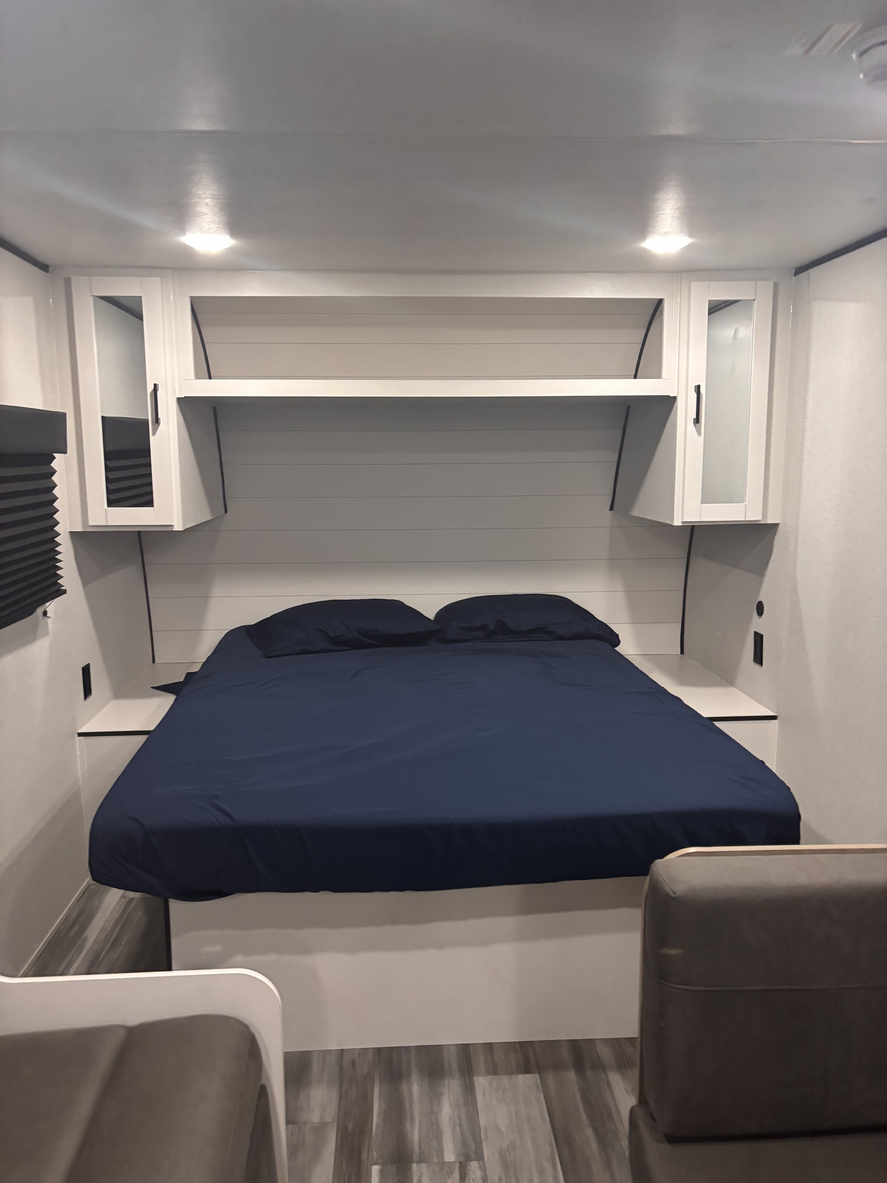 Cozy RV rental bedroom featuring a bed with navy linens, modern white cabinets, overhead storage, and clean design.. Jayco Jay Flight SLX Sport Edition 2026