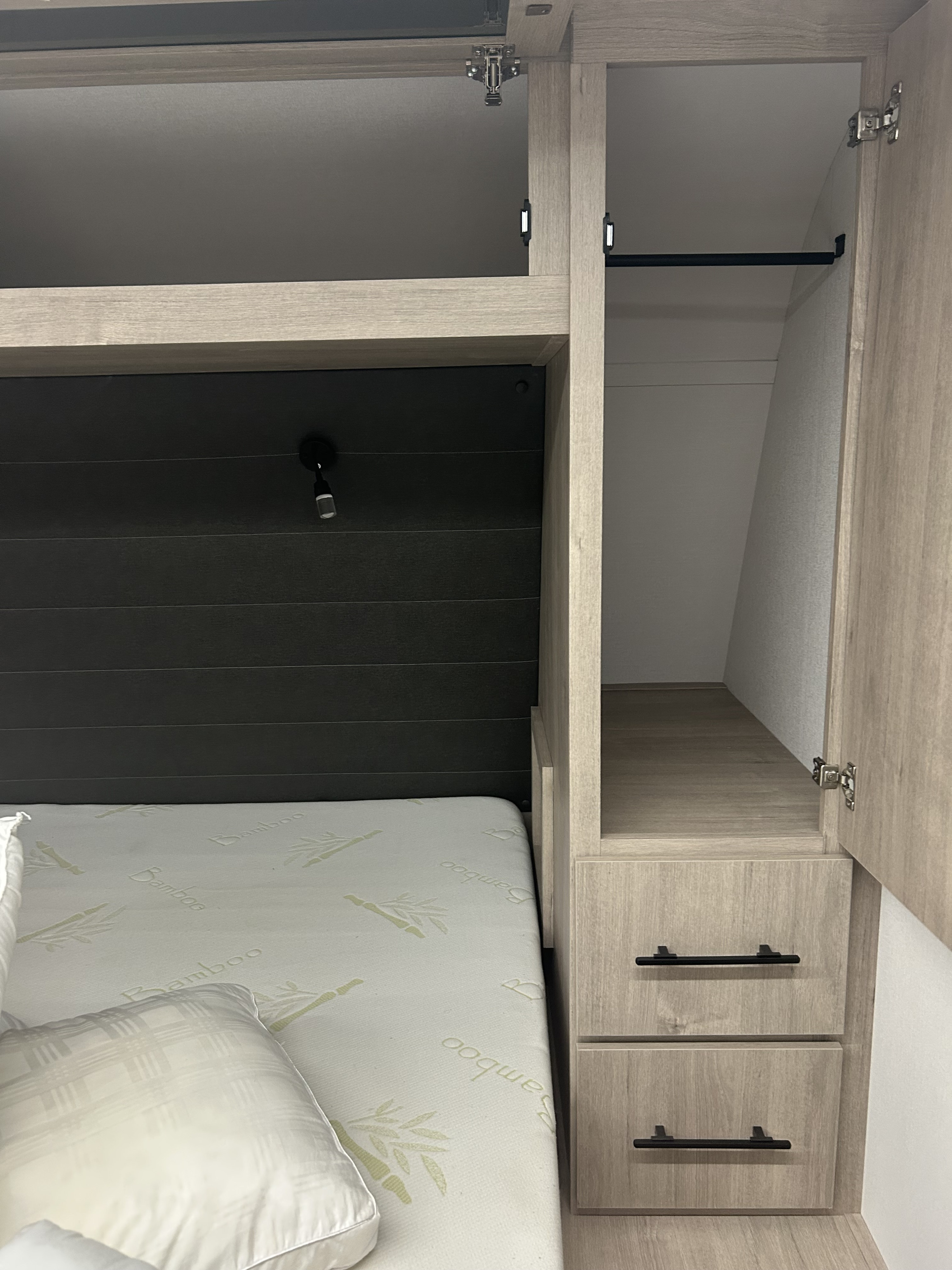 Cozy RV rental bedroom showcasing a Bamboo mattress, built-in storage with wardrobe, shelves, and drawers.. Grand Design Imagine 2026