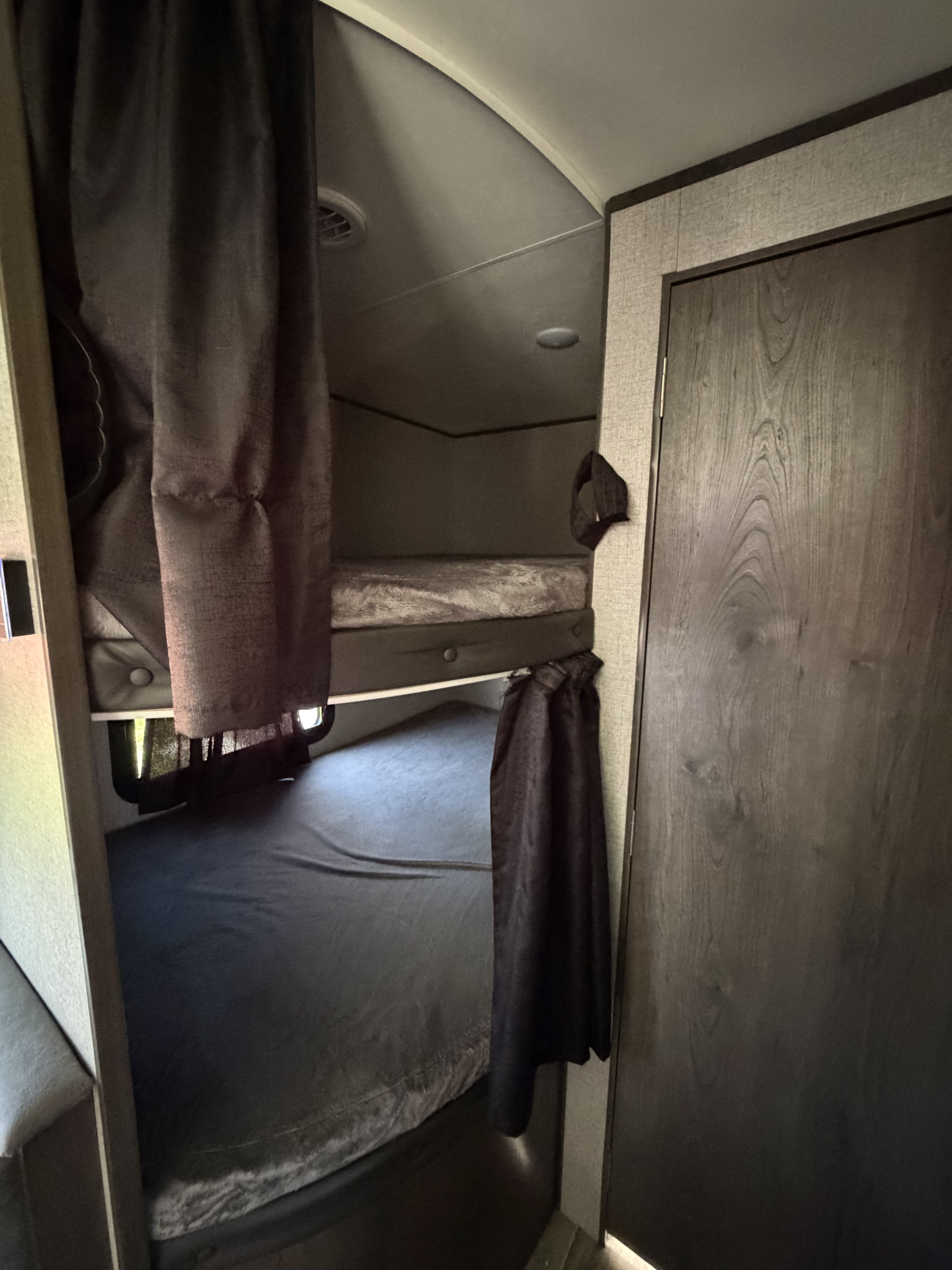 Cozy bunk beds with privacy curtains inside an rv rental, featuring a wooden door and curved ceiling.. Jayco Jay Flight SLX 2021