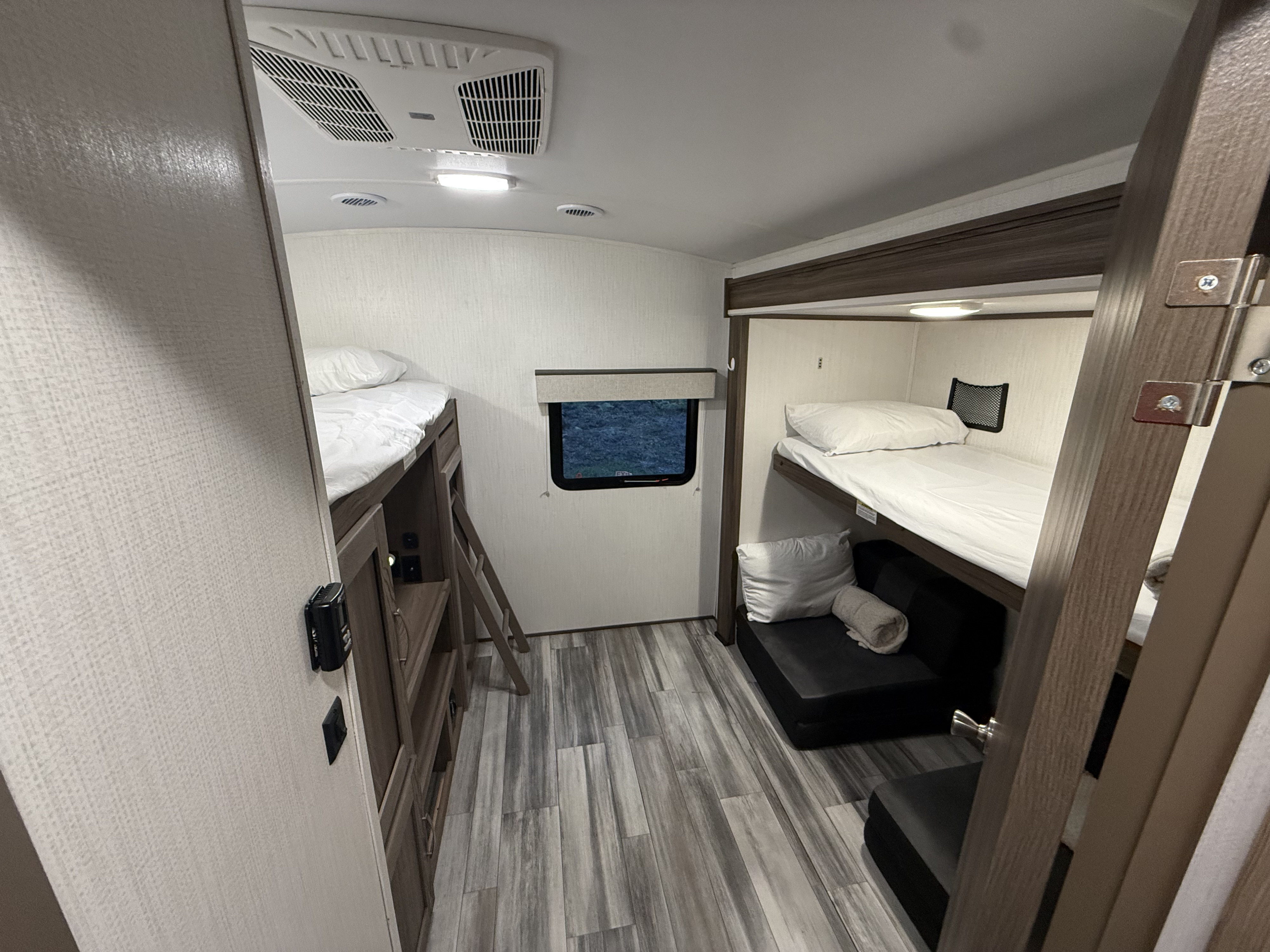Bright RV rental bunkhouse features bunk beds with white linens, a window, and stylish wood-look floors.. Twilight RVS Signature 2023