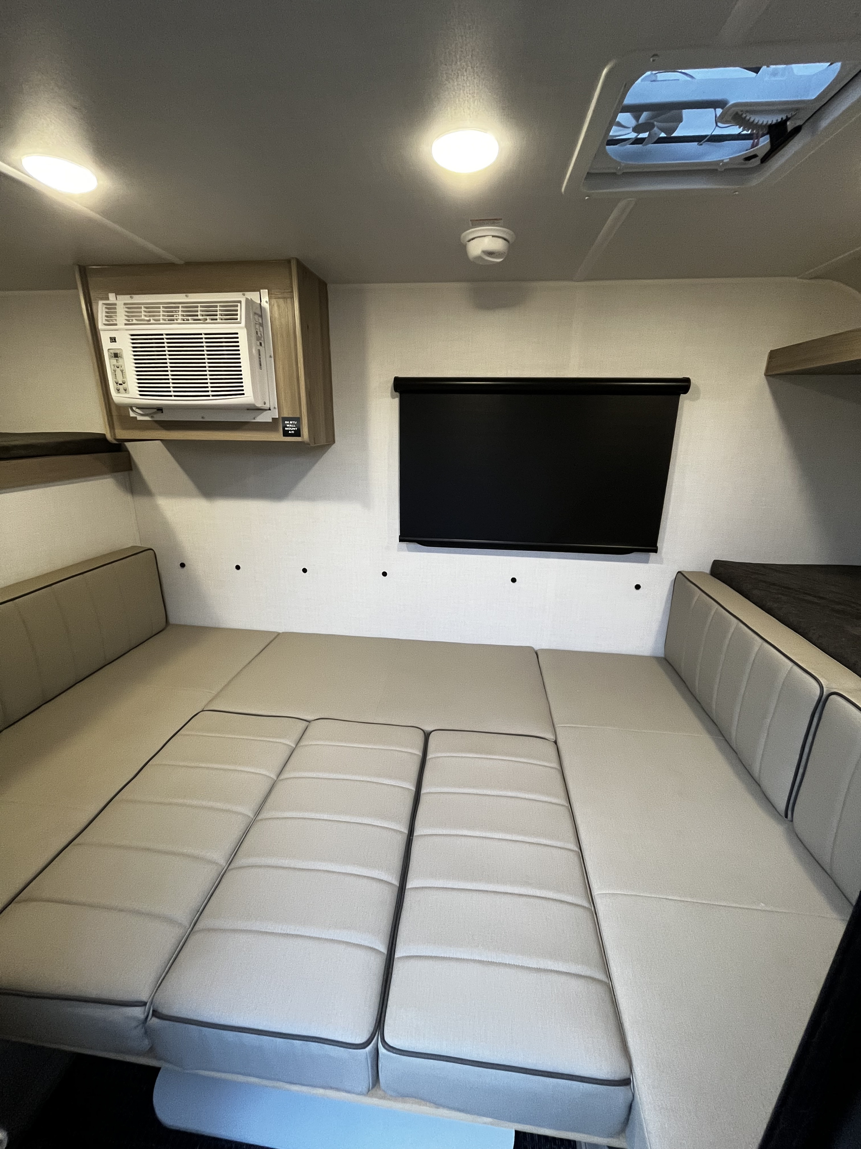 Interior of an rv rental, featuring a convertible bed/seating area, wall AC unit, retractable screen, ceiling lights, and a vent.. Forest River Flagstaff E-Pro 2026