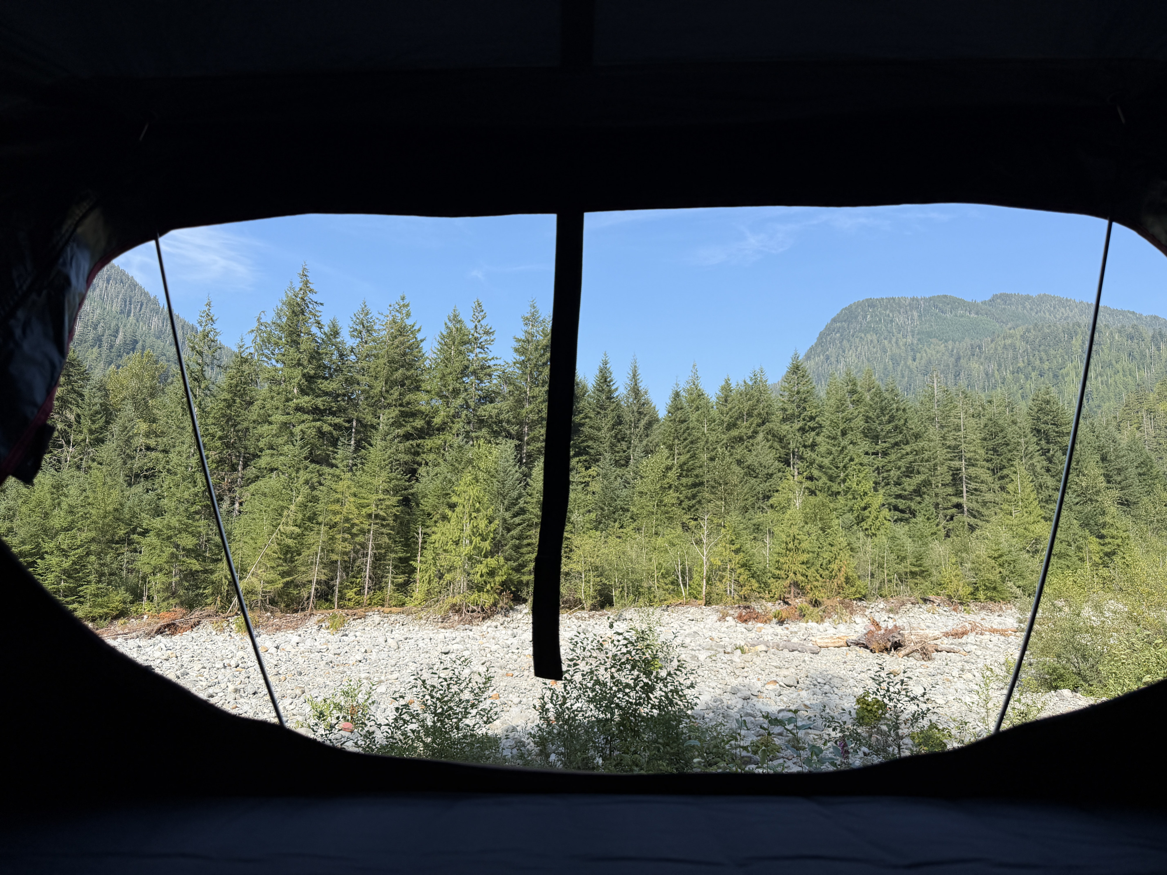 RV rental adventure: Your view from inside—forest, rocky riverbed, & mountains under a clear blue sky. Nature's doorstep.. Toyota Land Cruiser 2007