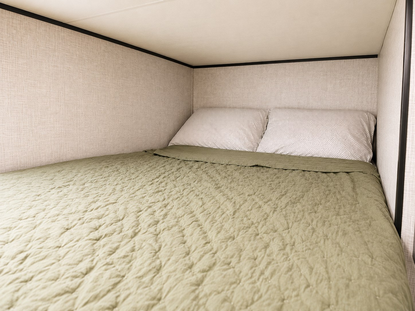 Inside an RV rental, a cozy bunk bed features a textured olive green quilt and two speckled white pillows.. Jayco Jay Flight SLX 2025
