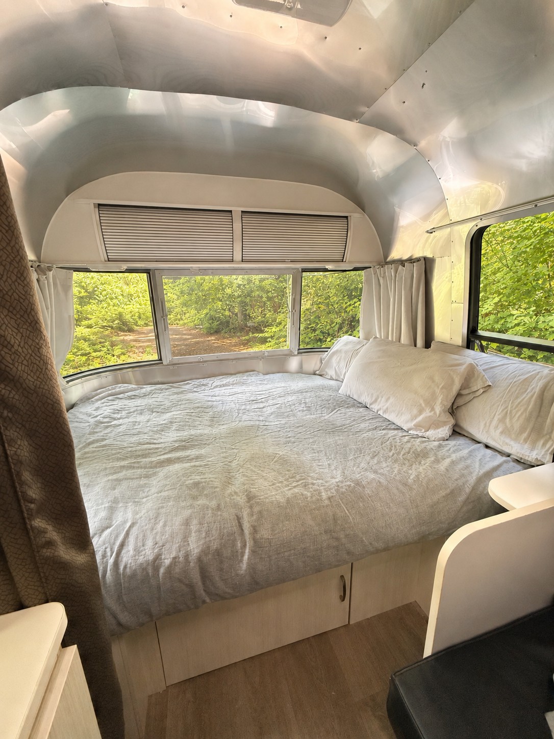 Cozy Airstream rv rental bedroom: comfortable bed, built-in storage, silver interior, and scenic green views from windows.. Airstream Sport 2019