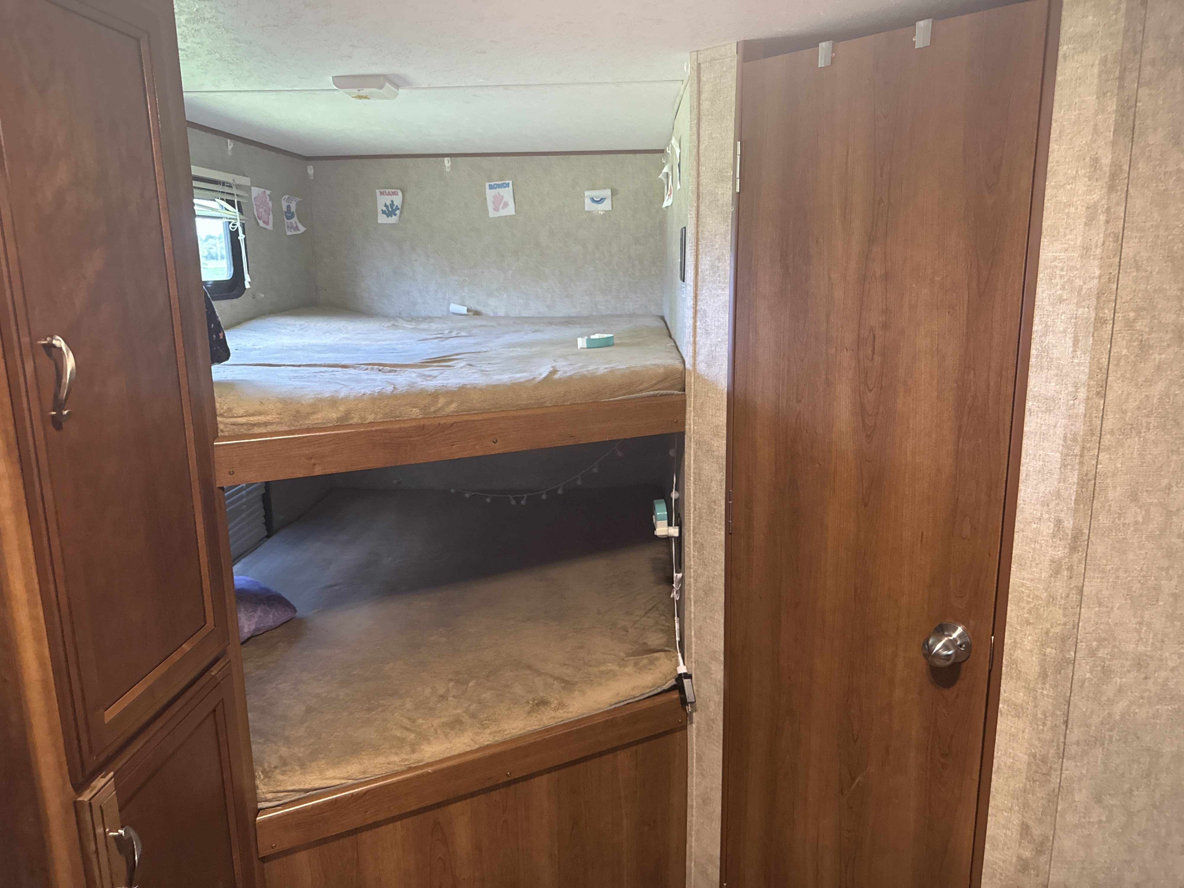 Inside an RV rental featuring bunk beds, a window, and wooden cabinetry, creating a compact sleeping area.. Avenger ATI 2016