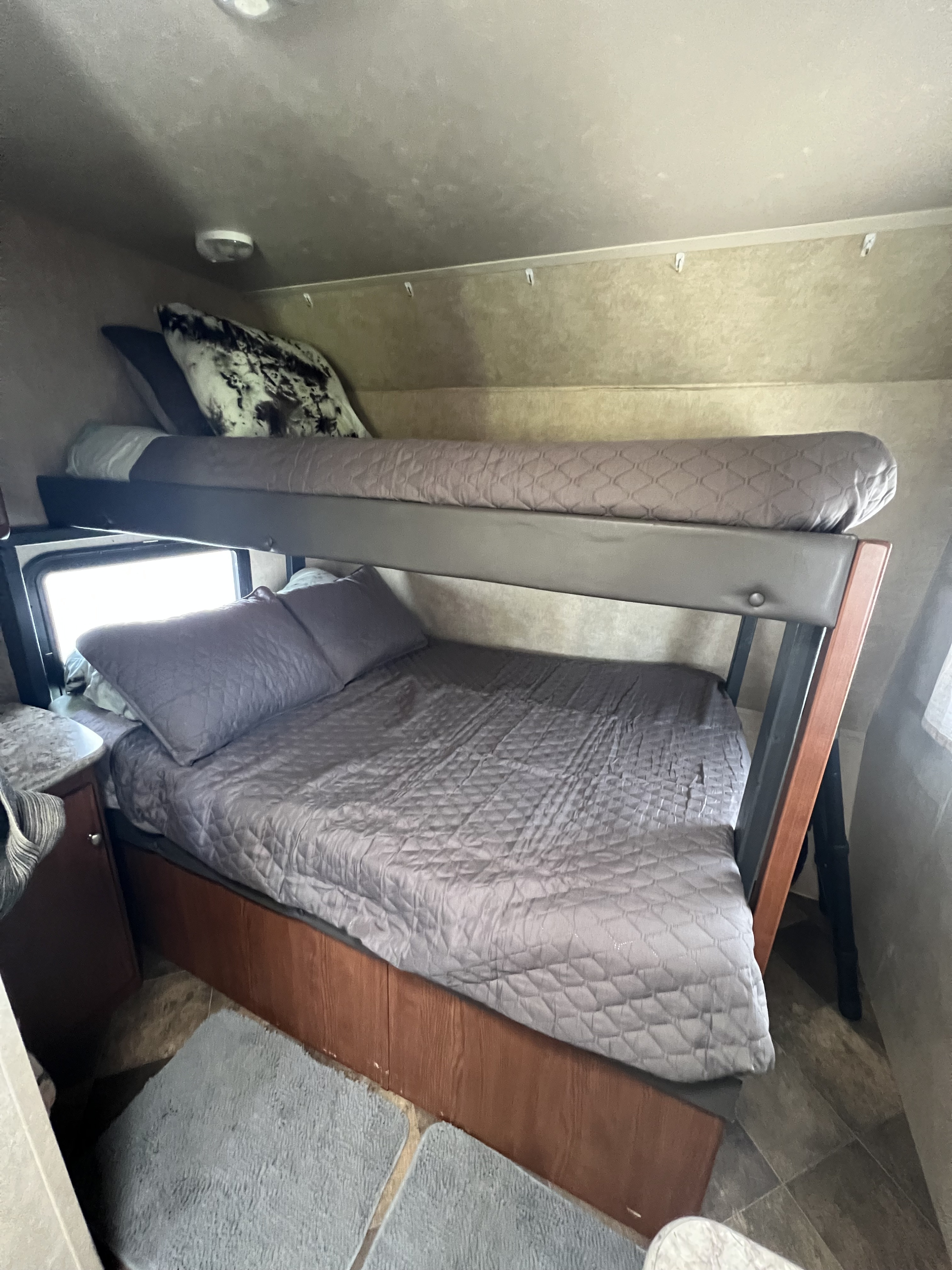 Cozy RV rental sleeping area featuring two bunk beds with matching grey bedding, ideal for travel.. Forest River Wildwood X-Lite FS 2015