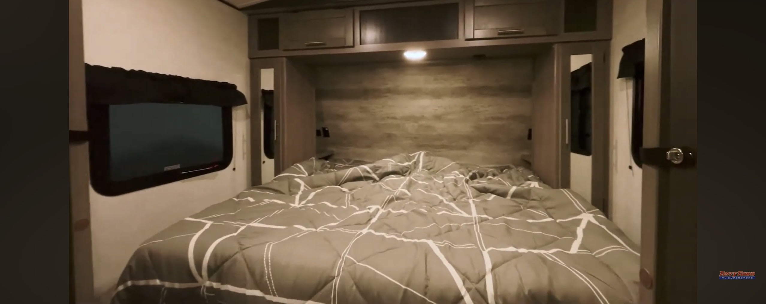 Cozy RV rental bedroom with a large bed, overhead storage, and a window. Perfect for your travel trailer adventures.. Crossroads RV Sunset Trail Super Lite 2022