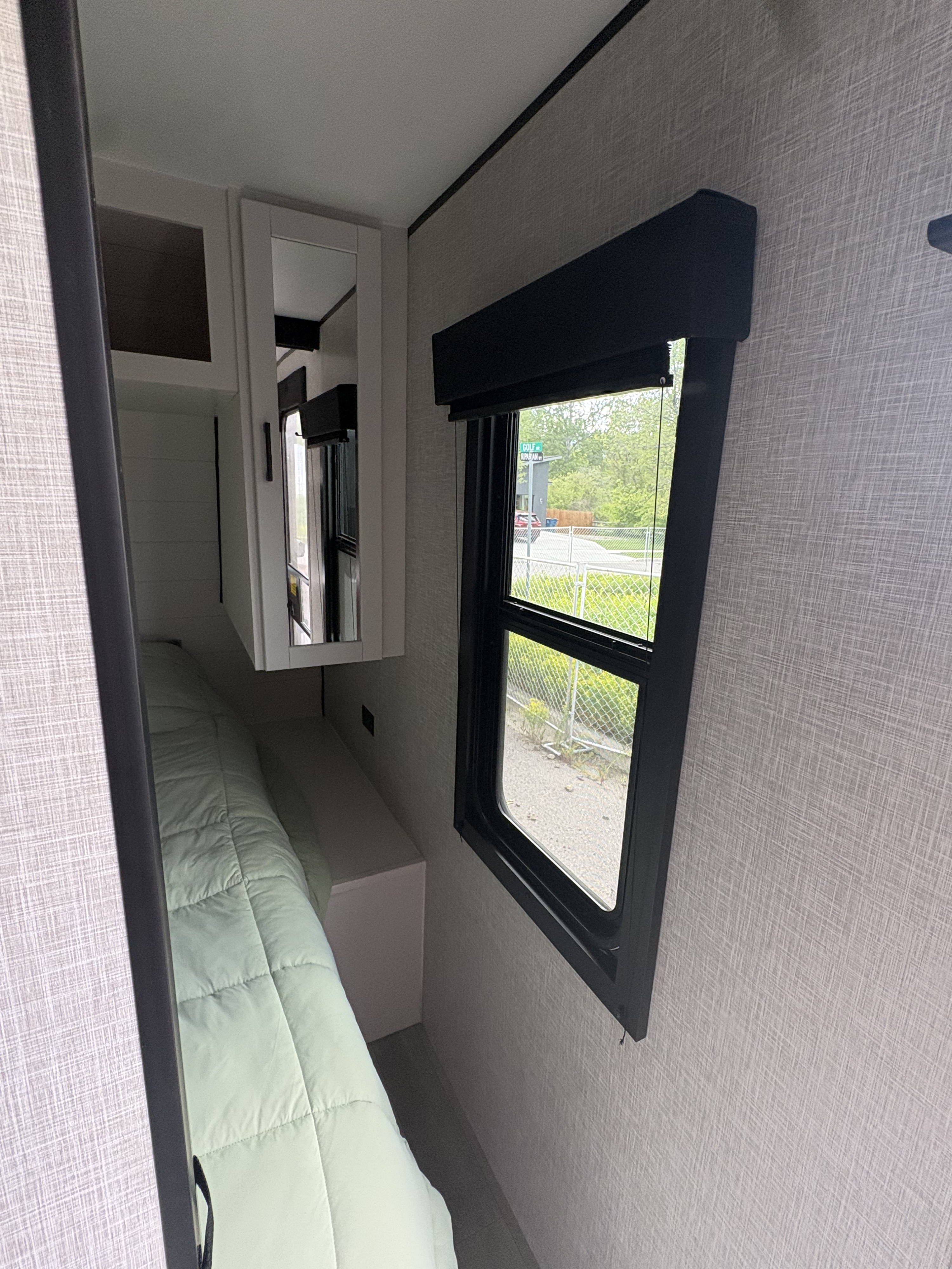 RV rental bedroom interior: light green bed, window with a view, and mirrored cabinet, offering a compact sleeping area.. FR3 FR3 Motorhome 2021