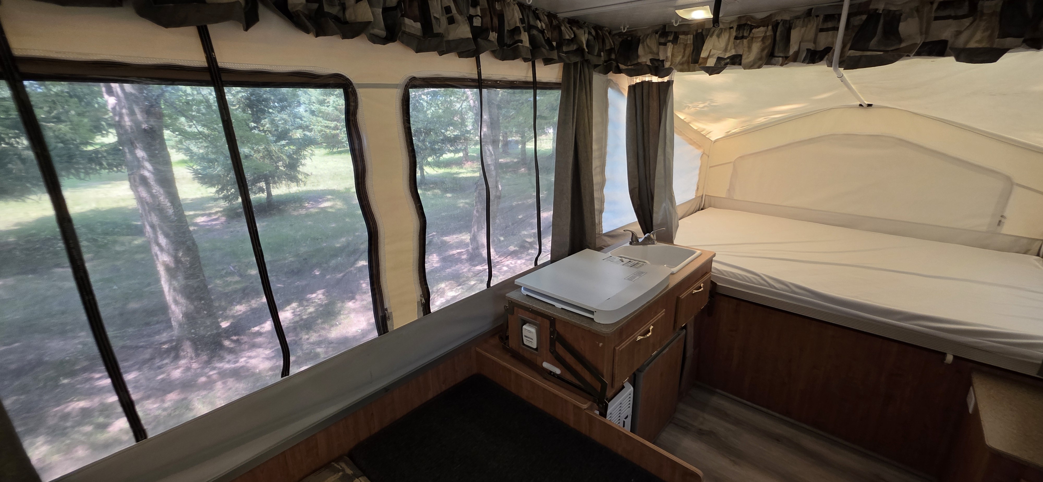 Inside an rv rental: pop-up camper with a compact kitchen, comfortable bed, and expansive views of trees and nature outside.. Forest River Rockwood Freedom 2008