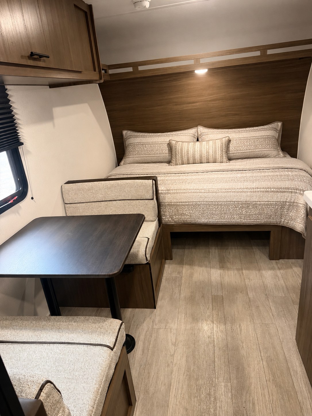 Relaxing RV rental interior with a cozy bed, booth dinette, and light wood finishes. Ideal for travel comfort.. Forest River Prime Time Avenger 16bhx 2027