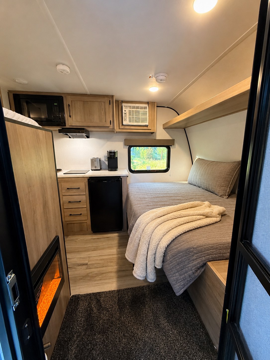 Experience comfort in this modern RV rental interior featuring a bed, kitchen, AC, and a cozy electric fireplace.. Keystone RV Coleman 2026