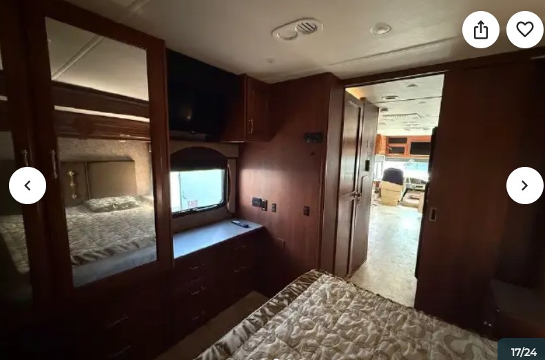 RV rental bedroom with bed, dresser, TV, mirror, and hallway view to the living area.. Fleetwood Southwind 2015