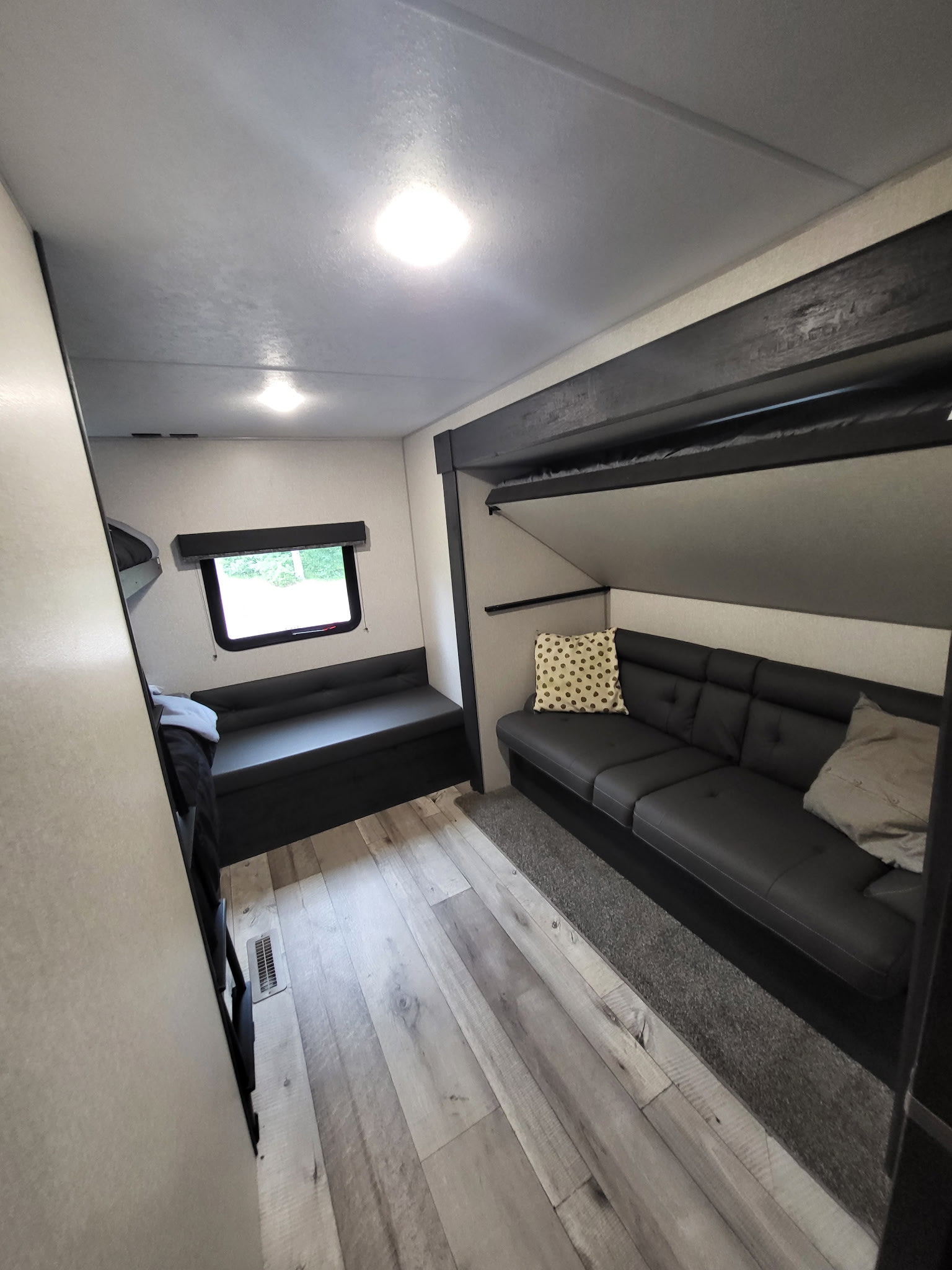RV rental interior featuring a modern living space with dark sofa, window seating, and bunk beds. Ideal for travel comfort.. KZ Sportsmen SE 332bkhse 2022