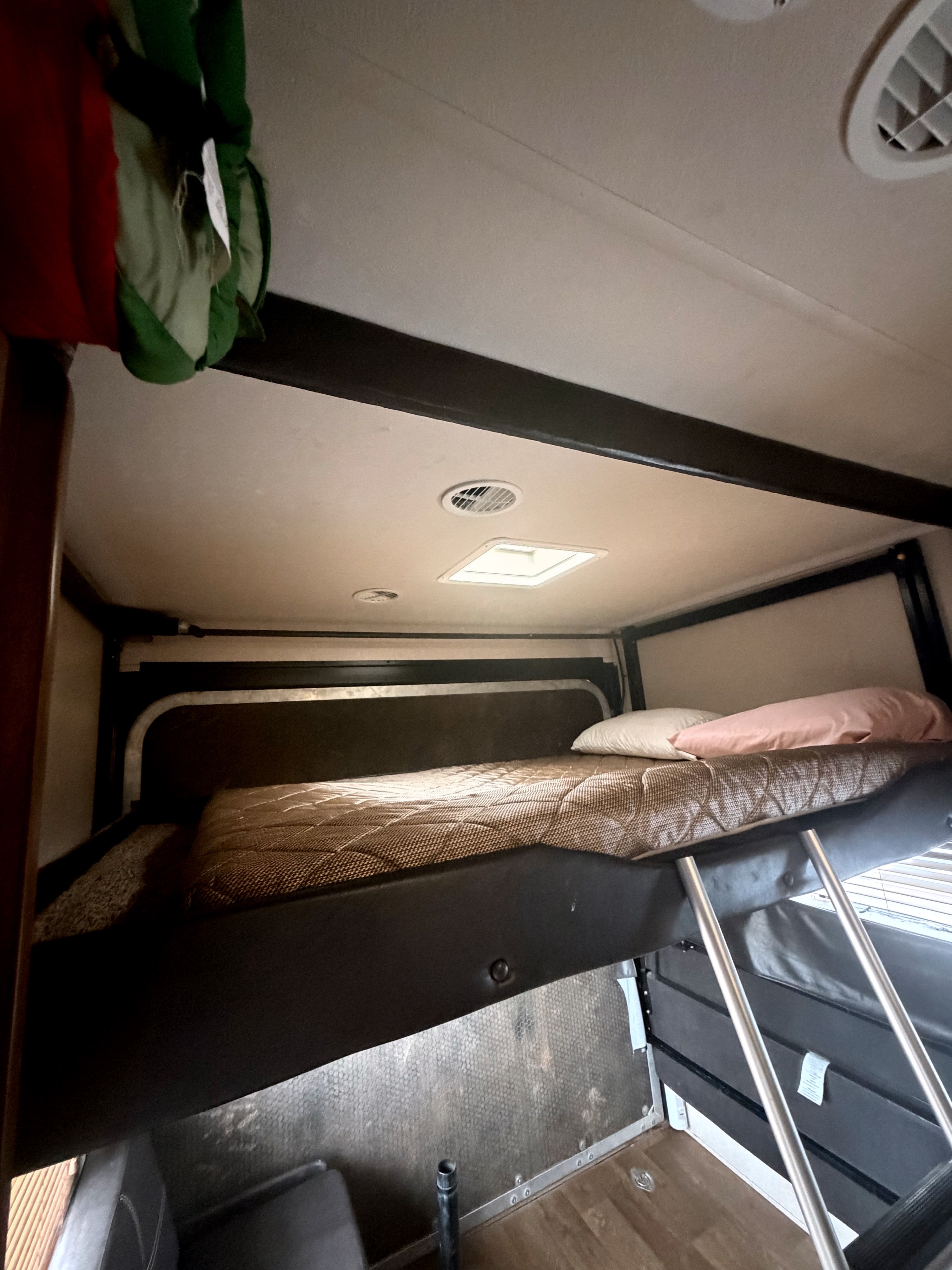RV rental interior showcasing a practical bunk bed with mattress, pillows, and an access ladder, ideal for extra sleeping.. Forest River Salem Cruise Lite 2018