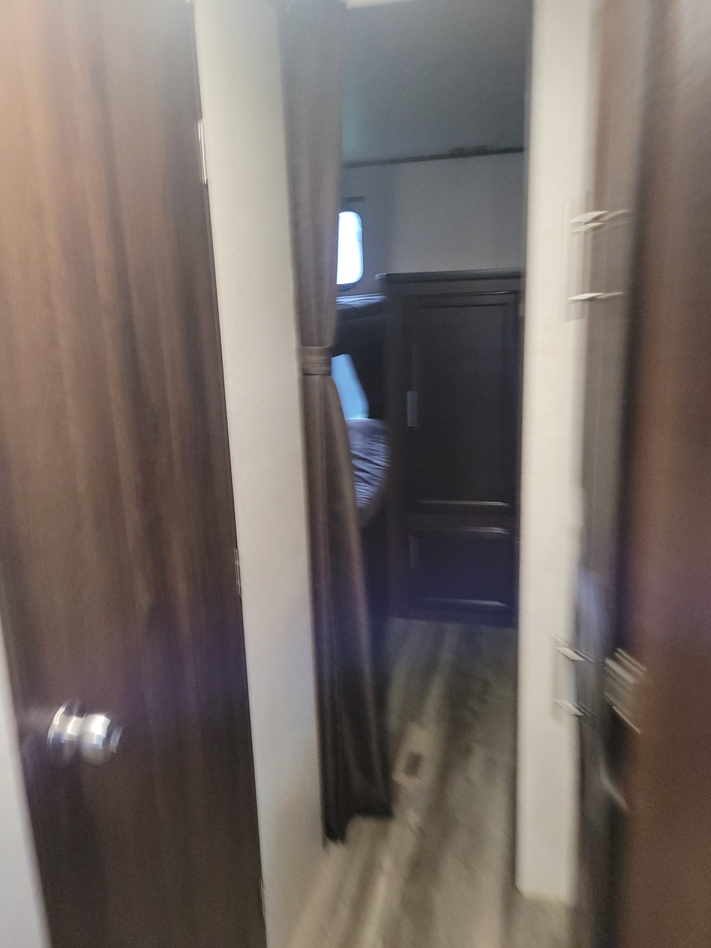 RV rental interior: A hallway leads to bunk beds, a window, and a cabinet, with dark wood doors and a curtain.. Jayco Jay Flight SLX 2019