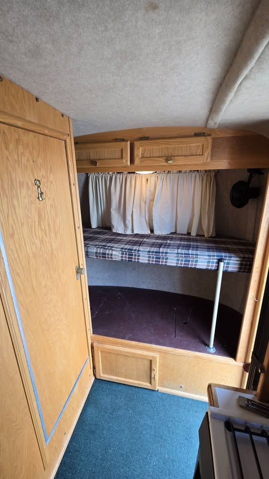 RV rental bunk beds and wooden cabinetry create a functional sleeping area inside this cozy camper interior.. Scamp Scamp Trailer 2004