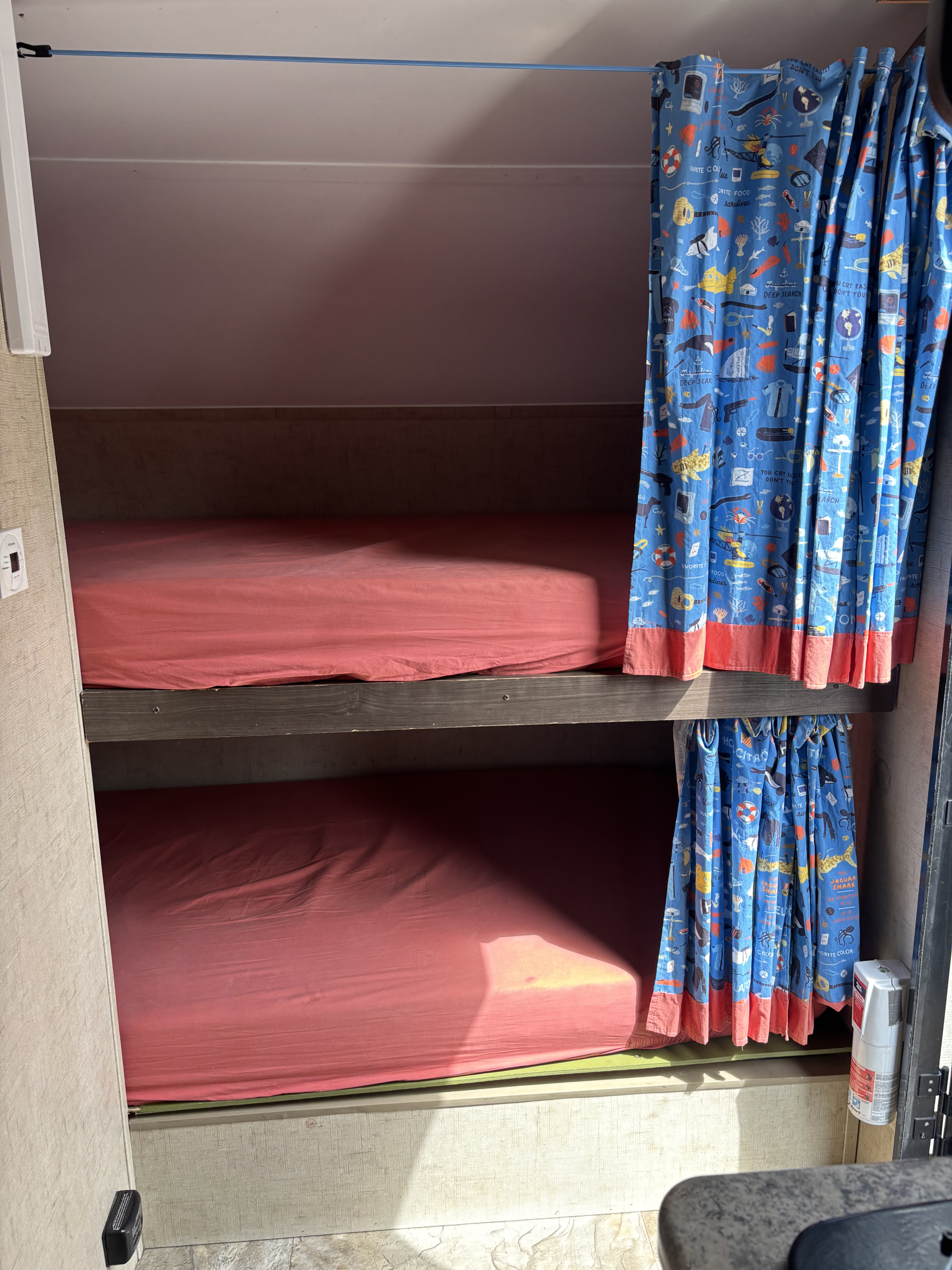 Cozy RV rental bunk beds with red sheets and fun blue curtains, perfect for family travel adventures.. R-Pod Hood River Edition 2016