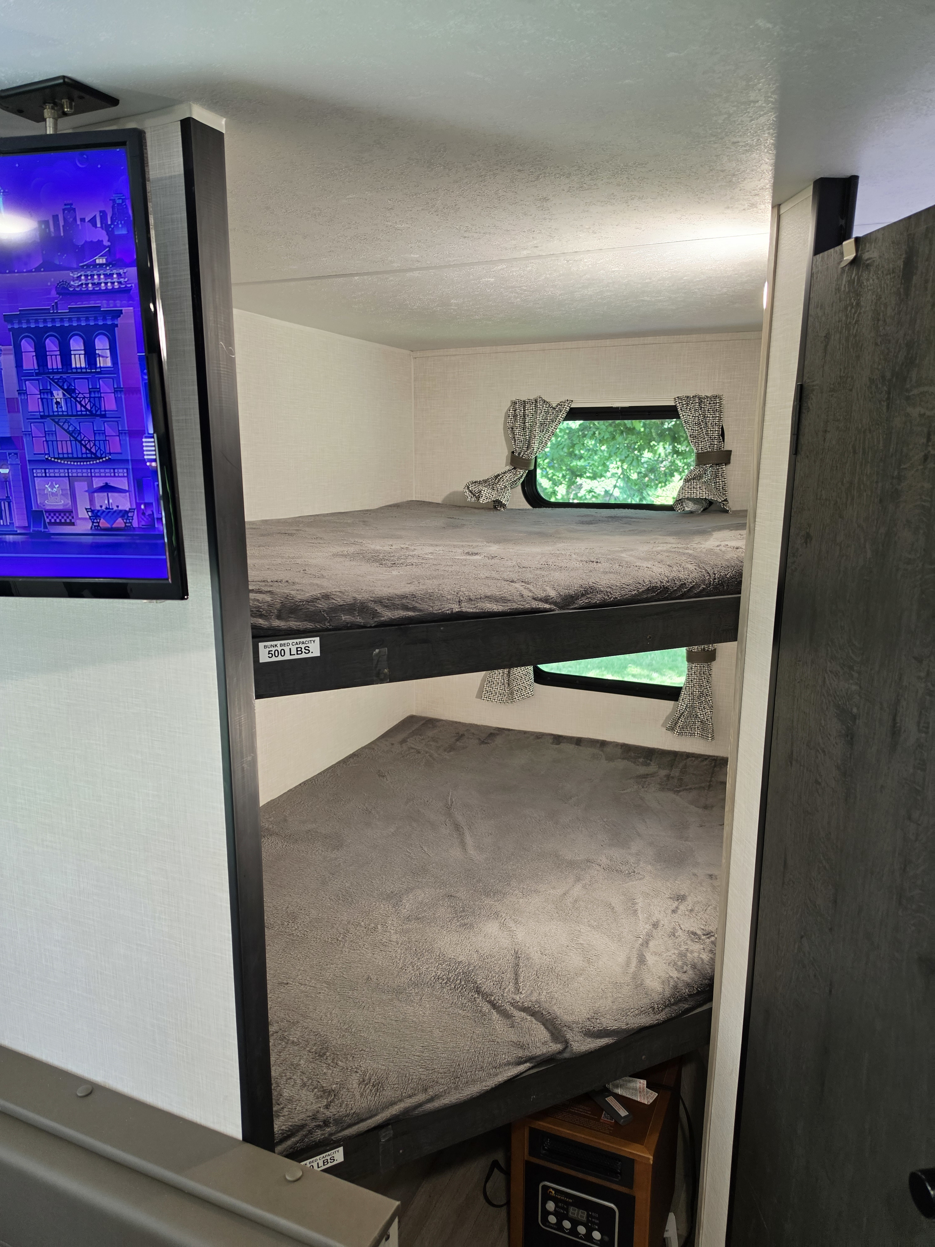 Inside an RV rental: cozy bunk beds with windows, soft blankets, and a TV for family adventures.. KZ Sportsmen 2024