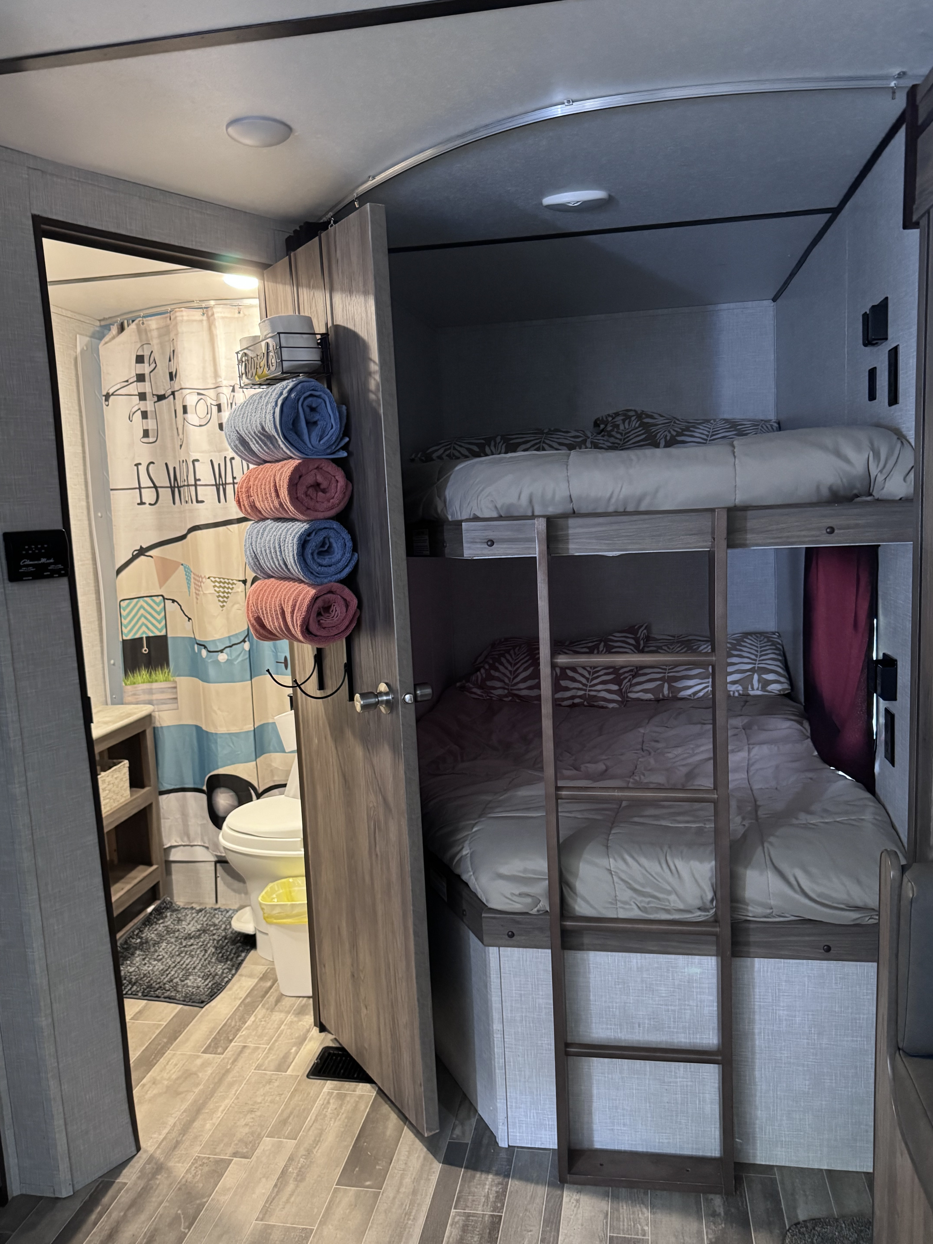 This RV rental interior features comfortable bunk beds on the right, and a compact bathroom with shower on the left.. Crossroads RV Zinger Lite 2021