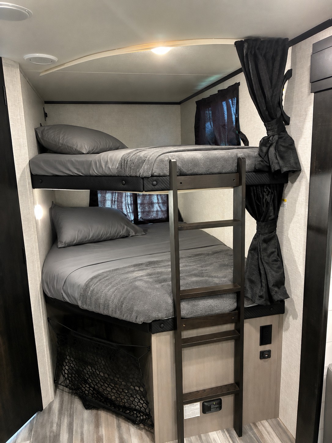 RV rental: Compact gray bunk beds with ladder and dark curtains, offering a cozy sleeping area inside the camper.. Jayco Jay Feather 2024