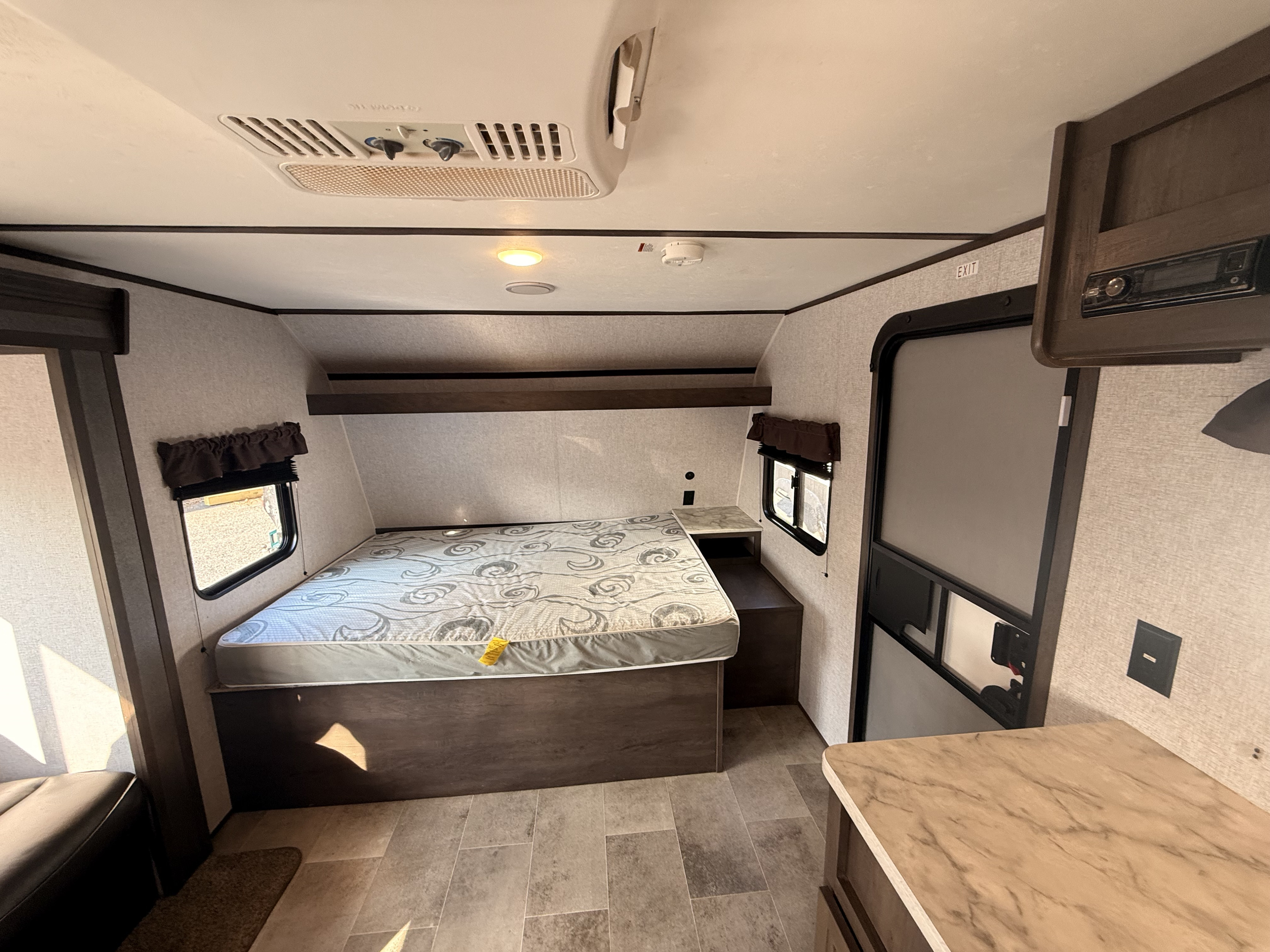 RV rental bedroom interior featuring a comfortable bed, windows, AC unit, and media console. Perfect for your trip.. Dutchmen Coleman Lantern LT 2021