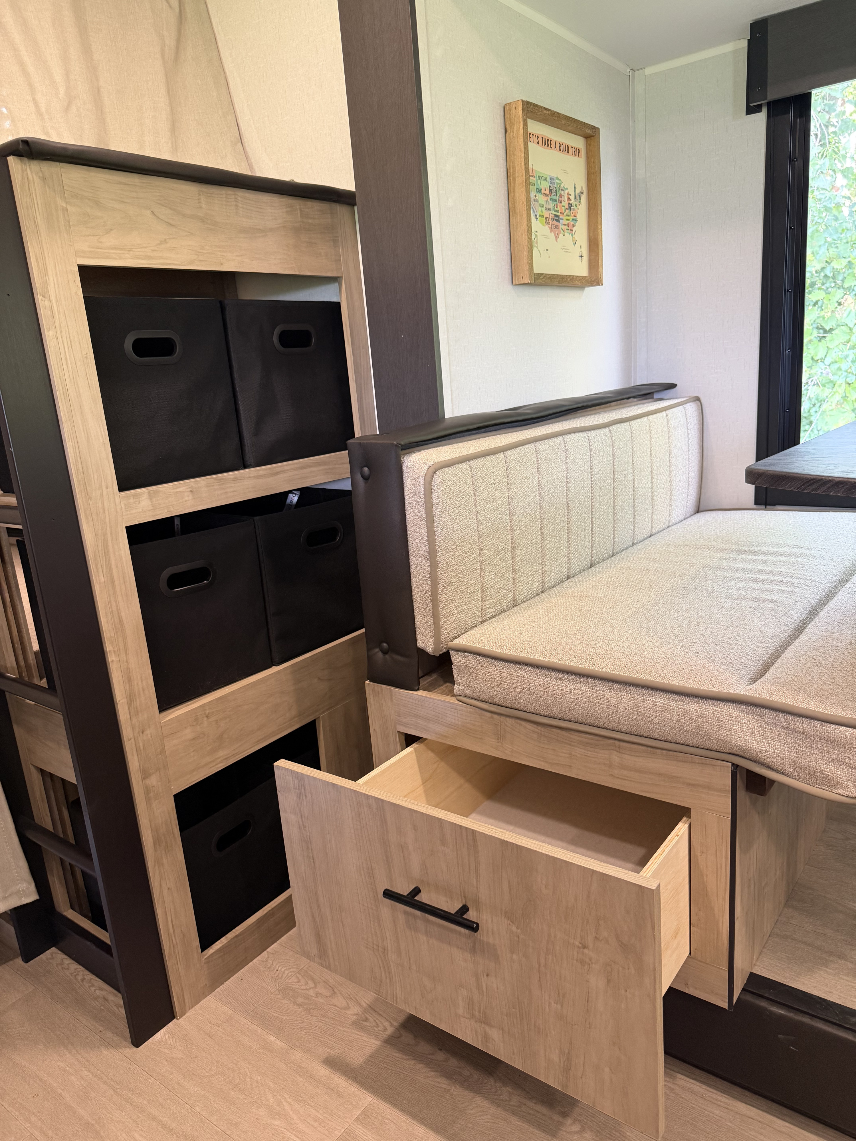 Cozy RV rental interior featuring bunk beds with storage bins, a dinette with an open drawer, and a "Road Trip" map.. Forest river Campsite Reserve 26cj 2027