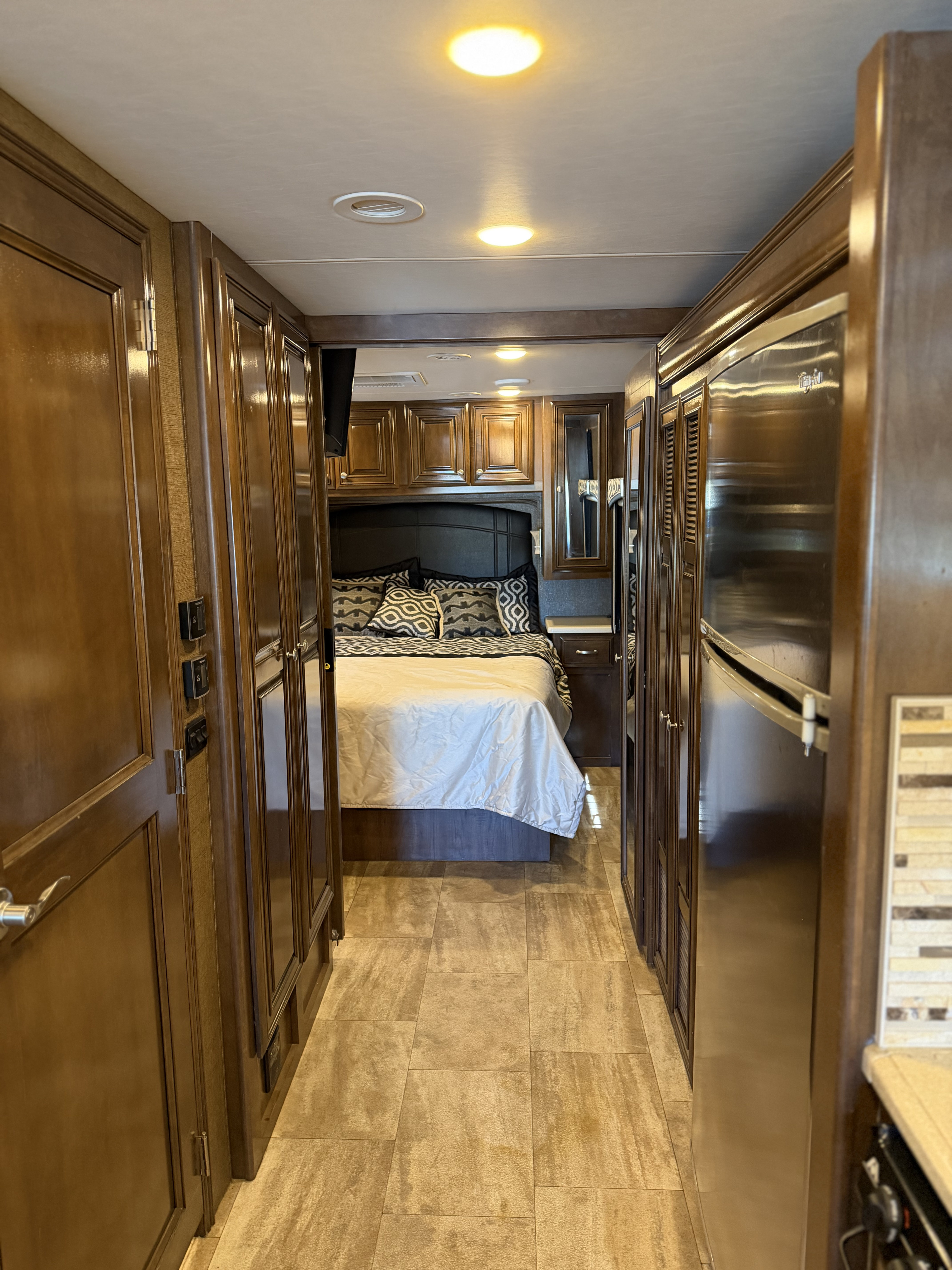 RV rental: Hallway leading to a cozy bedroom with warm wood cabinetry, tiled floor, and a fridge on the right.. Thor Palazzo 2017