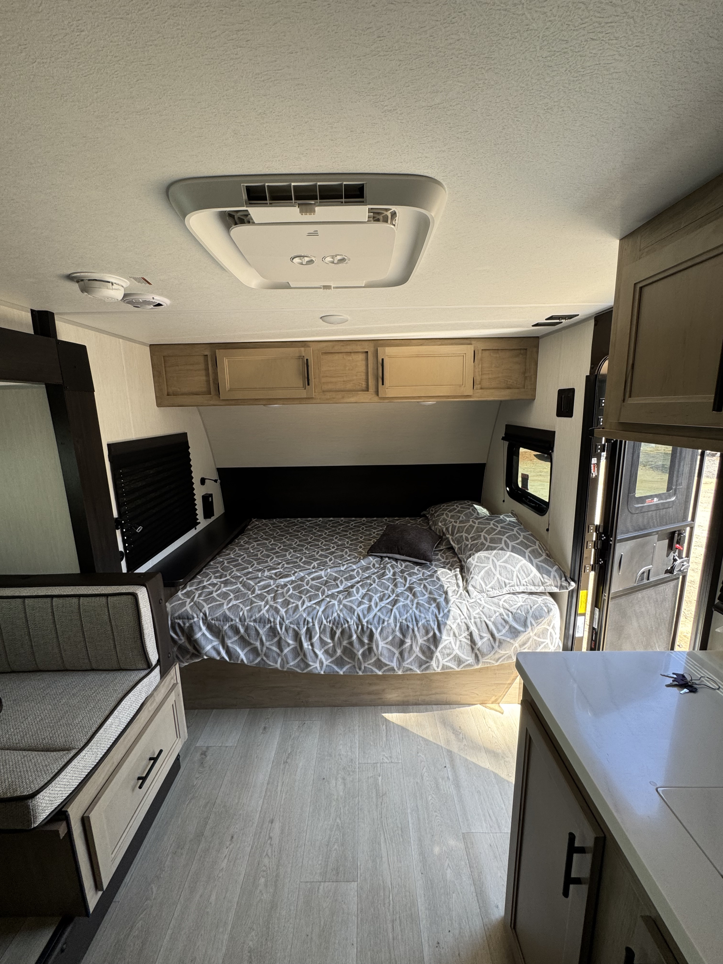 Inside an rv rental: a compact bedroom with a patterned bed, overhead cabinets, and a side dinette.. Forest River Cherokee Wolf Pup 2026