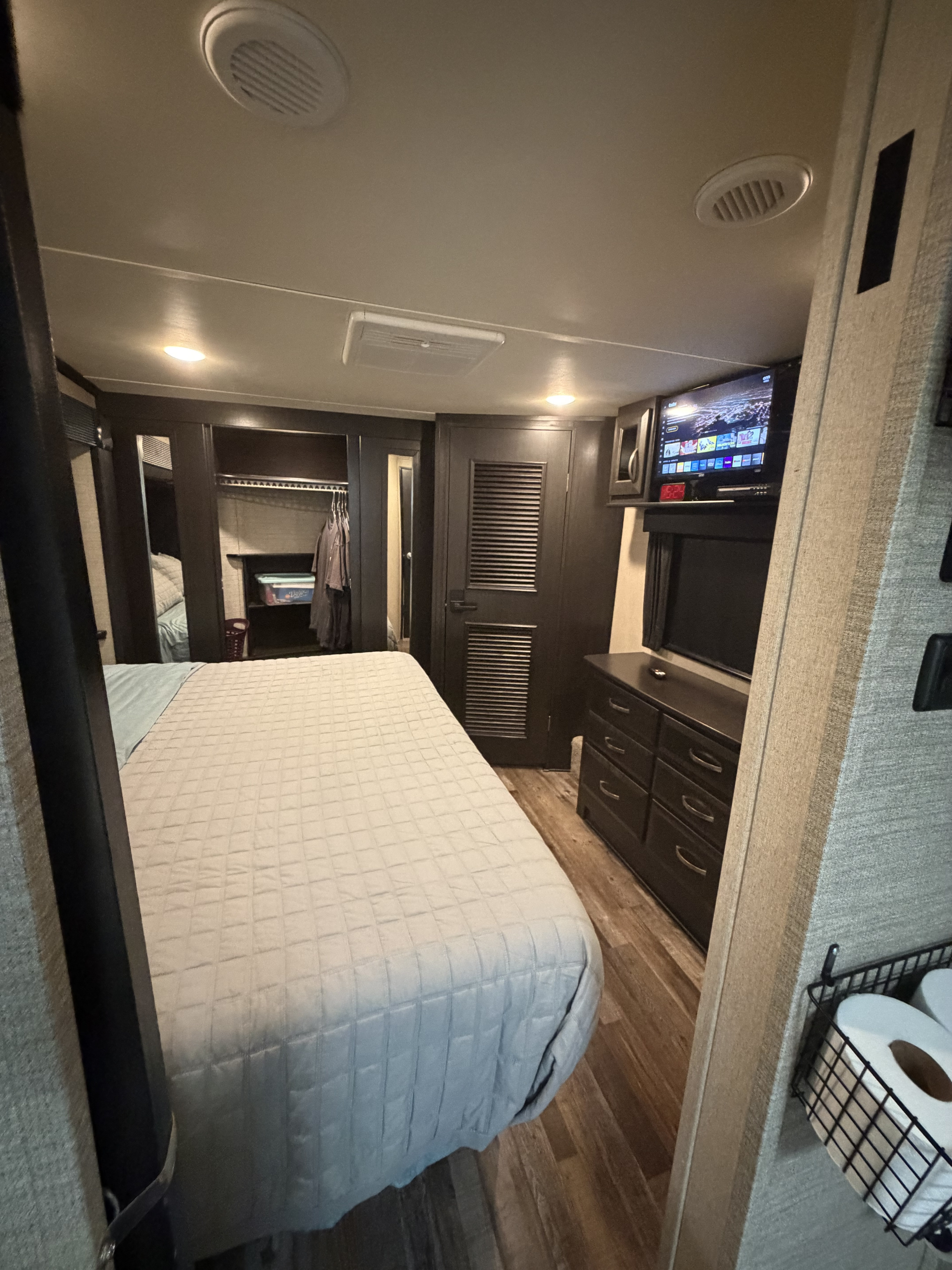Cozy rv rental bedroom with bed, TV, closet, dresser, ceiling vents, and recessed lighting. Toilet paper in storage basket.. Denali Denali Fifth Wheel 2017
