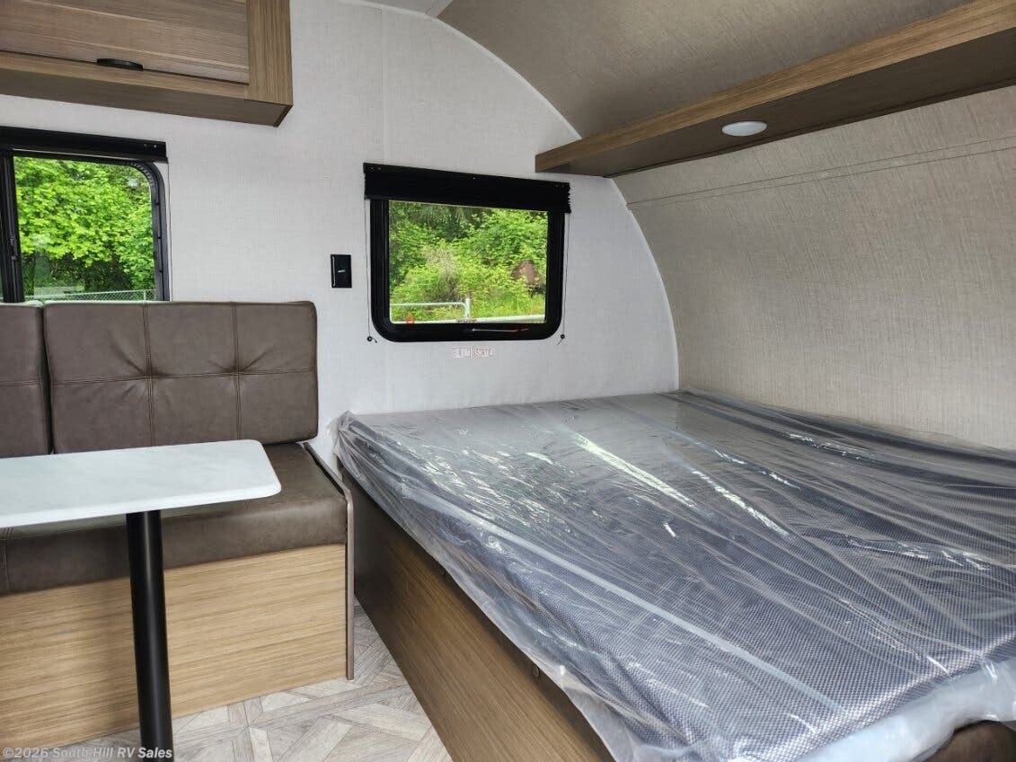 Inside this RV rental: a new bed (still in plastic), a dinette, and windows showing green views. Perfect for travel.. Forest River Salem FSX 2025