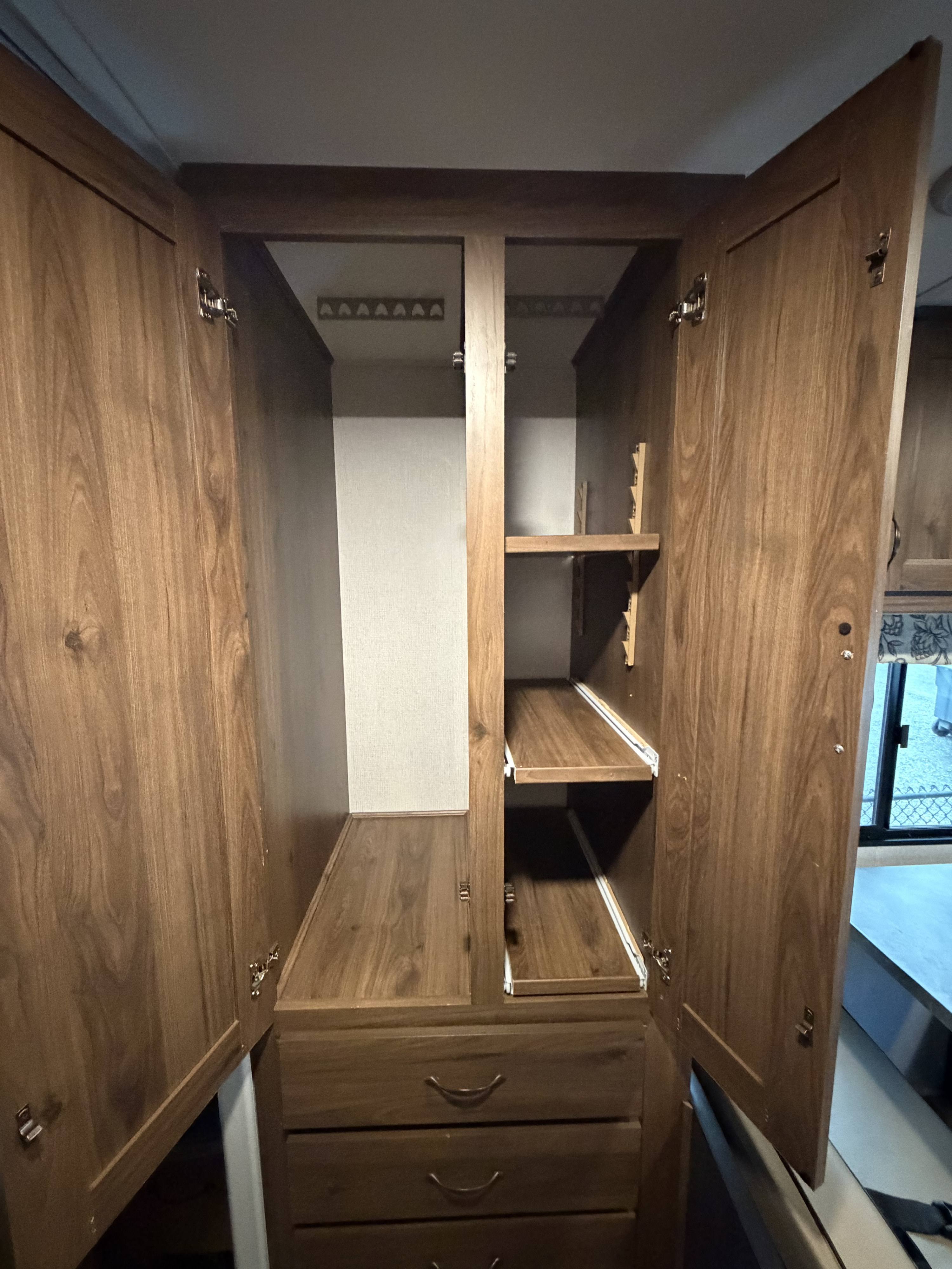 RV rental wardrobe with open doors, revealing a spacious closet, adjustable shelves, and three drawers for organized storage.. Forester LE 2020