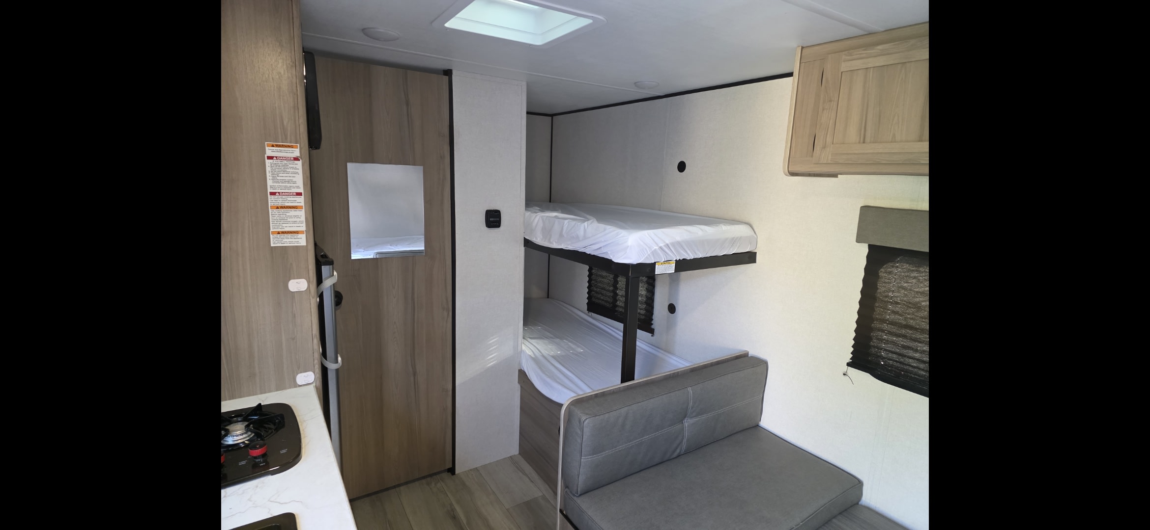 RV rental interior: a cozy space with bunk beds, a compact kitchen, and a dinette area. Ready for your next camper adventure!. Keystone RV Coleman 2025