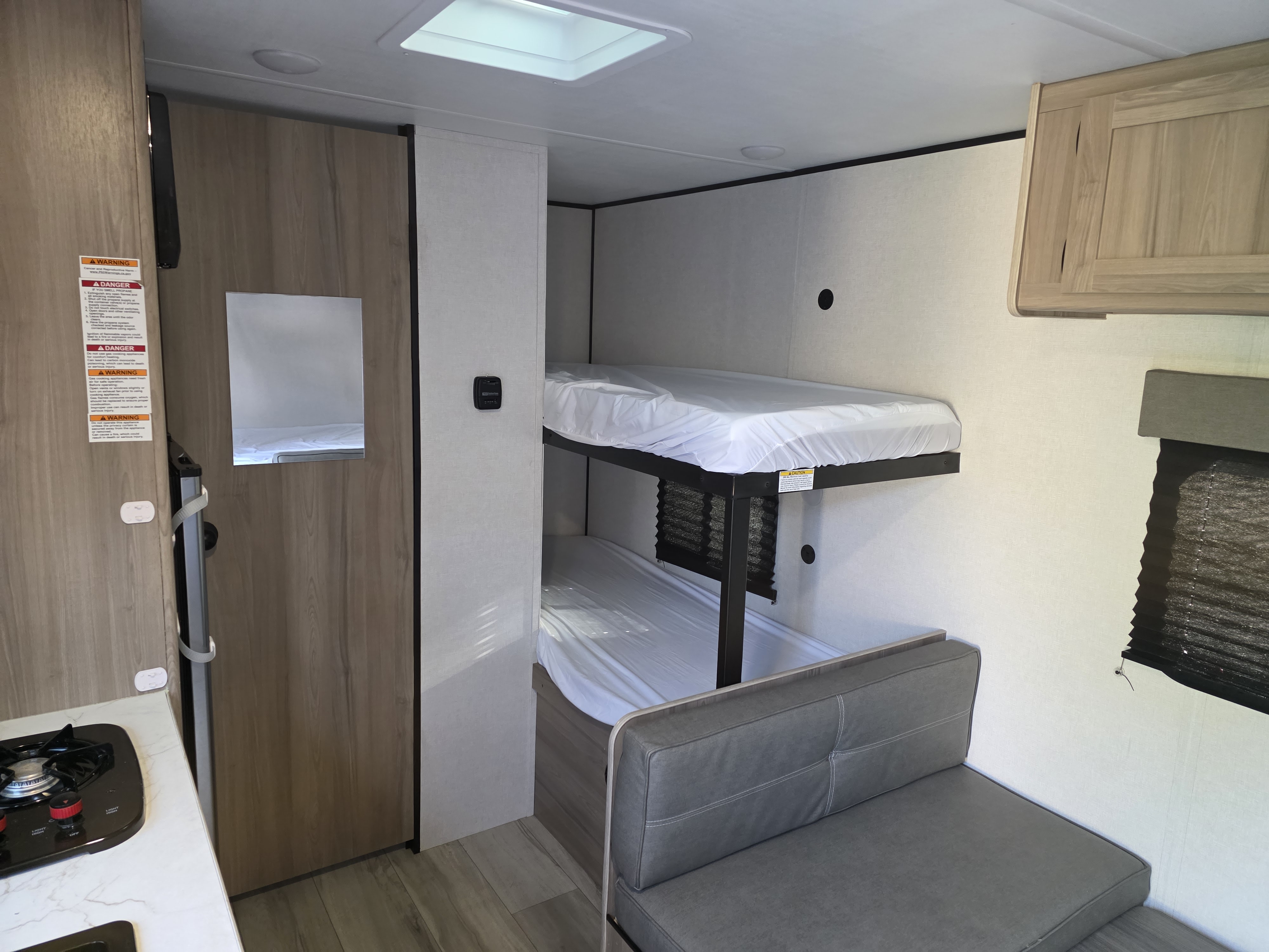 This RV rental interior offers practical bunk beds, a dinette, and a kitchenette. Perfect for compact camper travel.. Keystone RV Coleman 2025