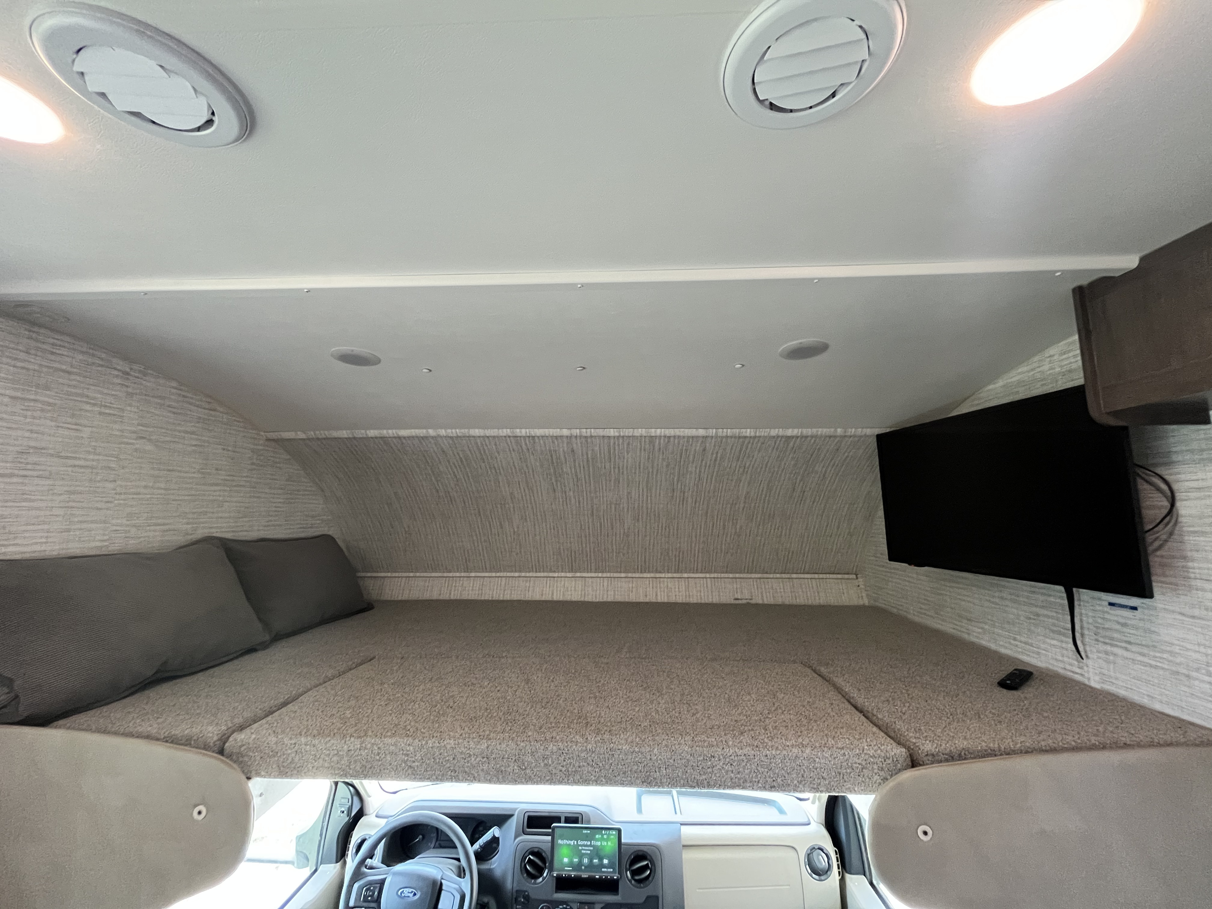 RV rental interior: View of the cab-over bunk bed with pillows and TV, offering a cozy sleeping space above the cockpit.. Jayco Redhawk SE 2024