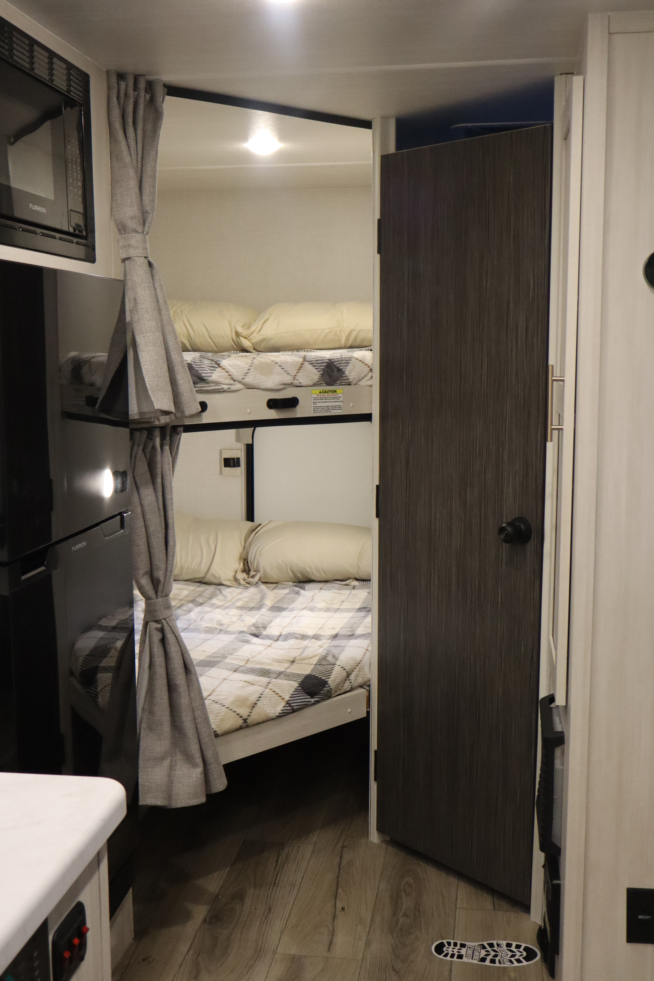 Cozy RV rental bunk beds visible within a compact travel trailer interior, complete with microwave and modern wood flooring.. R-Pod R-Pod Trailer 2026
