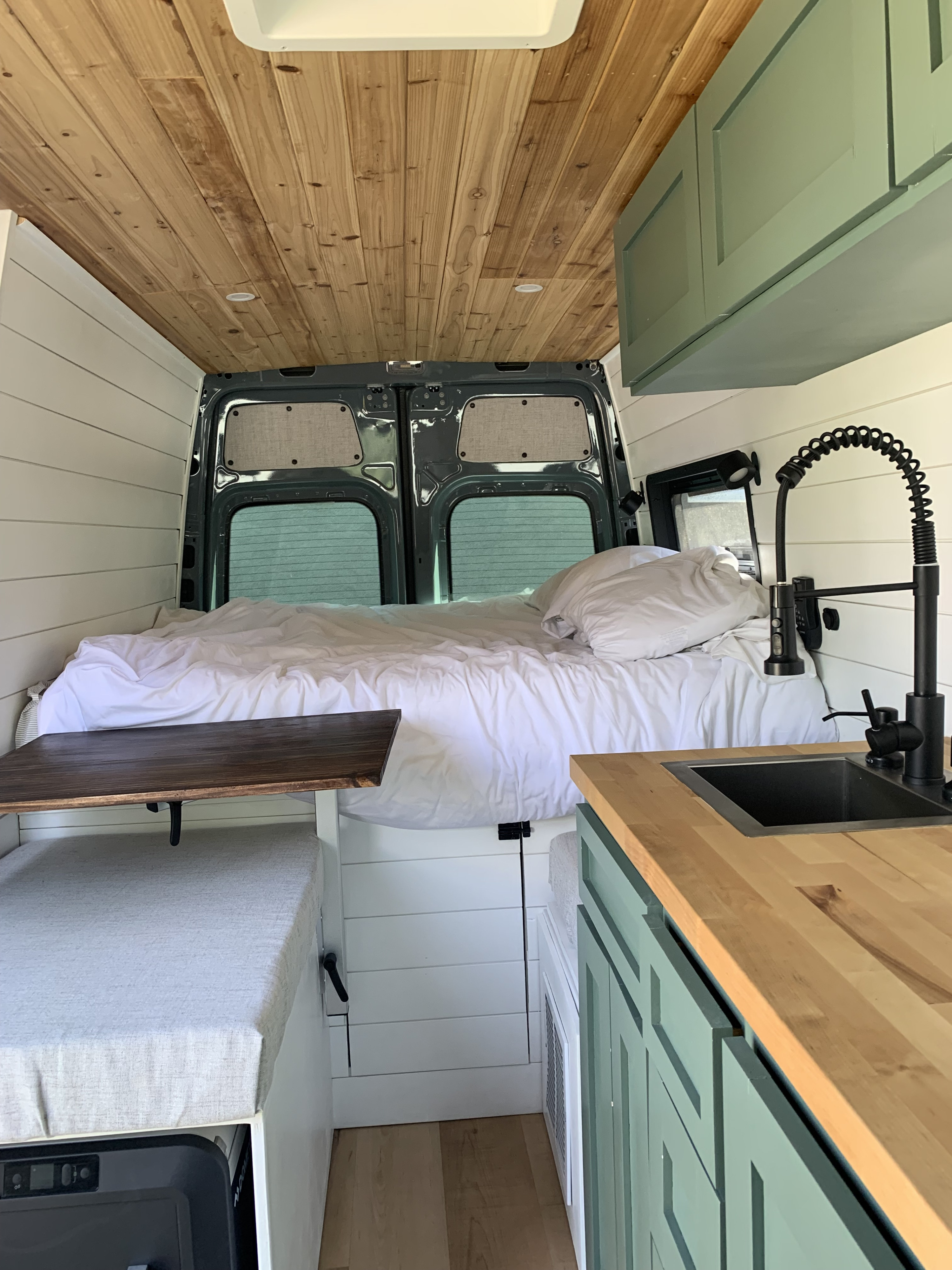 RV rental: Cozy camper van interior with a bed, kitchenette, wood ceiling, and sage green cabinets.. Mercedes-Benz Sprinter 2021