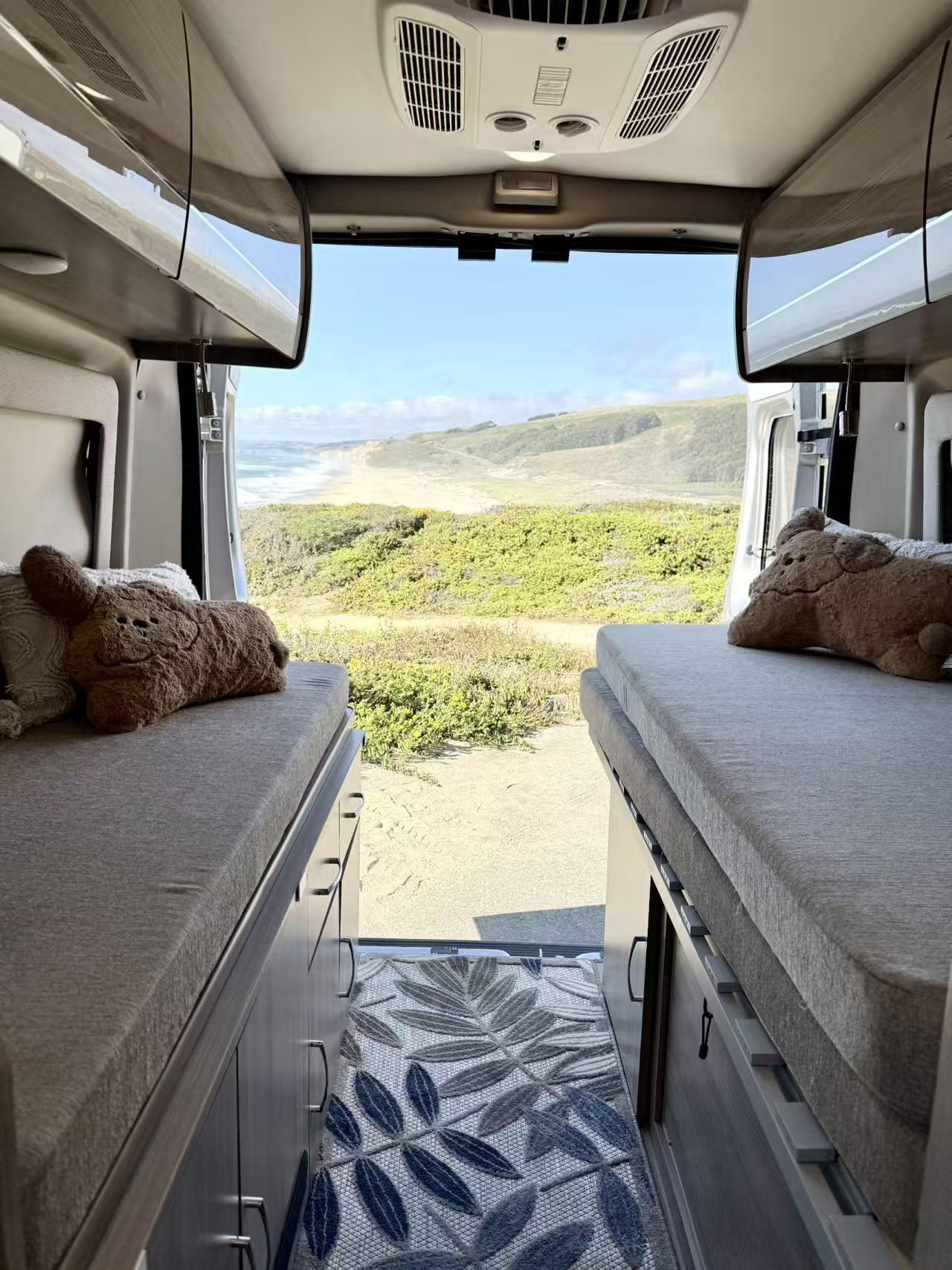 Experience scenic tranquility in this RV rental. Twin beds offer comfort, leading to an expansive ocean and beach view.. Thor Sequnce 2023