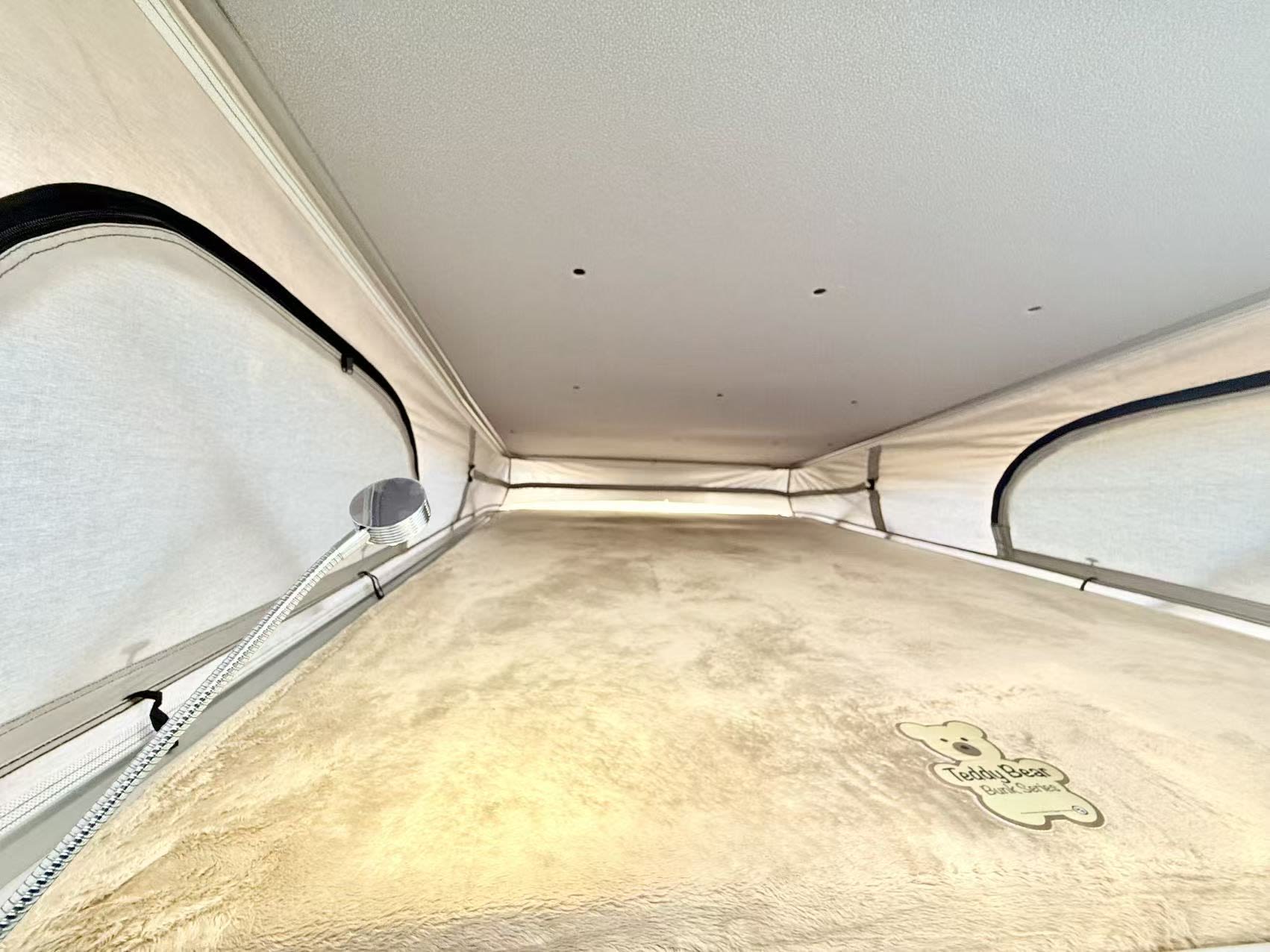 RV rental's pop-top sleeping area: a plush 'Teddy Bear Bunk Series' mattress and flexible light in this cozy camper.. Thor Sequnce 2023
