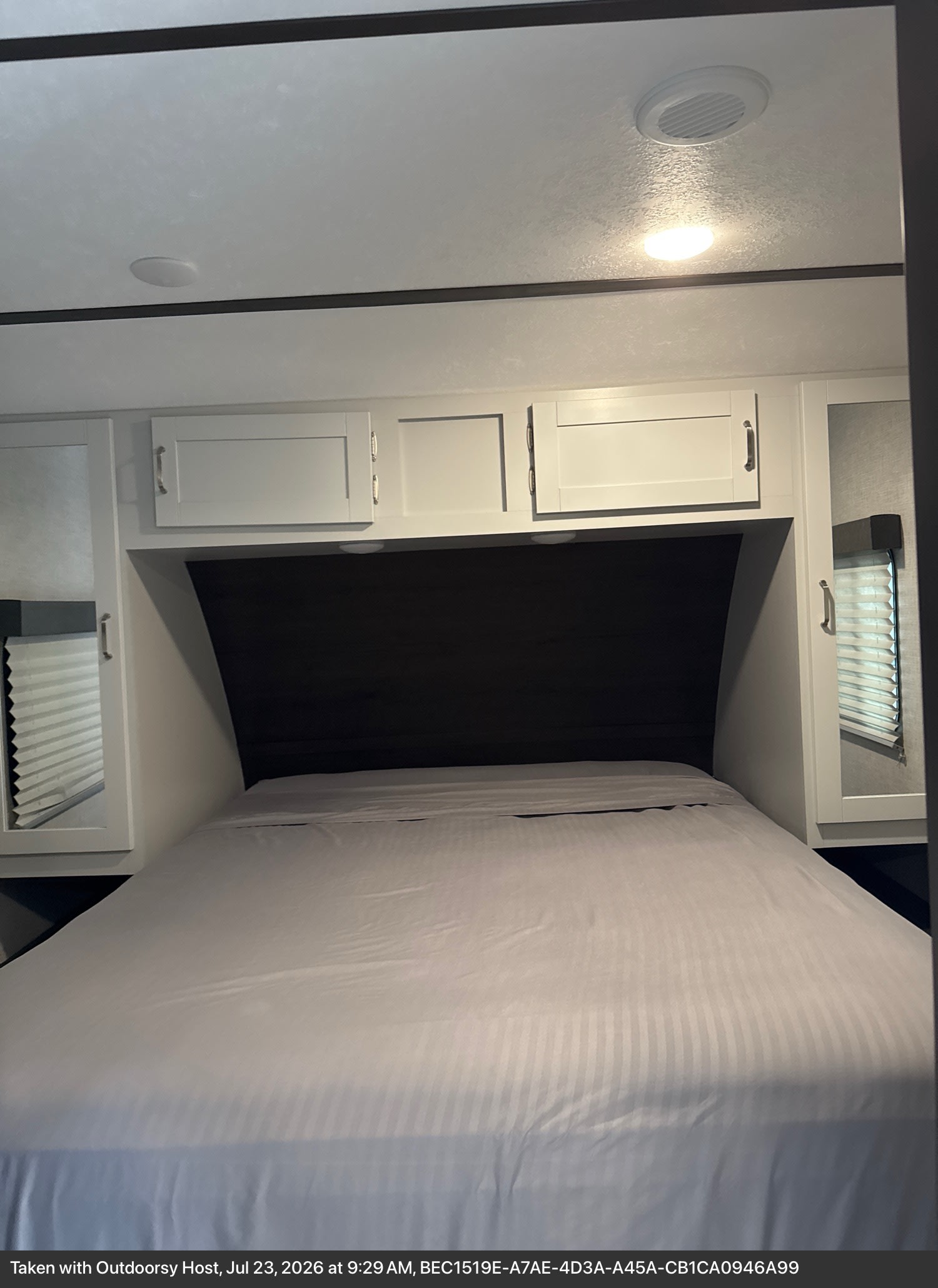 Spacious RV rental bedroom with a comfortable bed, mirrored side wardrobes, and overhead cabinets for ample storage.. Keystone RV Bullet Ultra Lite 2020