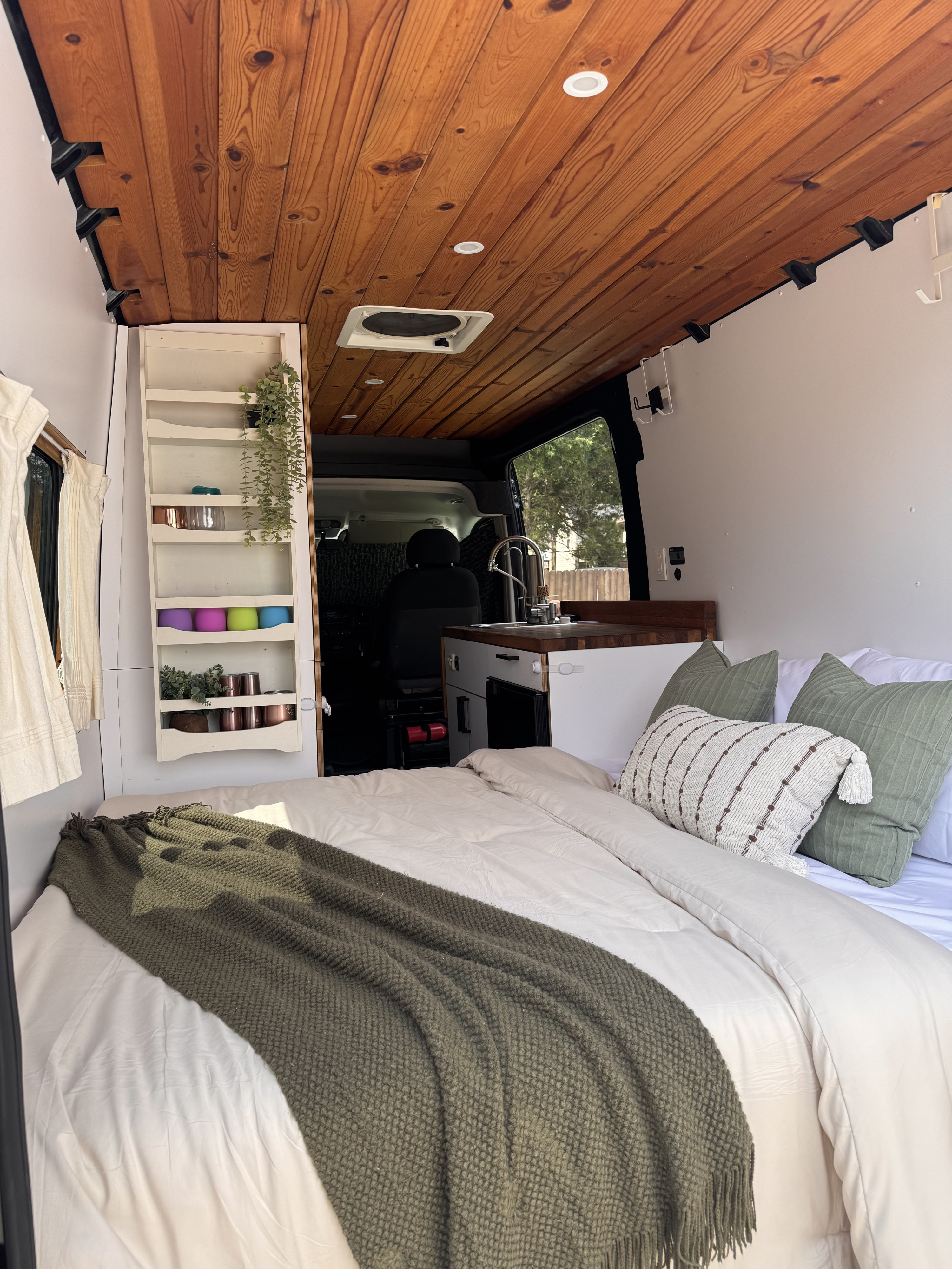 Step into this cozy rv rental camper van, featuring a comfy bed, wood-paneled ceiling, and a compact kitchen. Ideal for van life.. Dodge Sprinter Van 2019